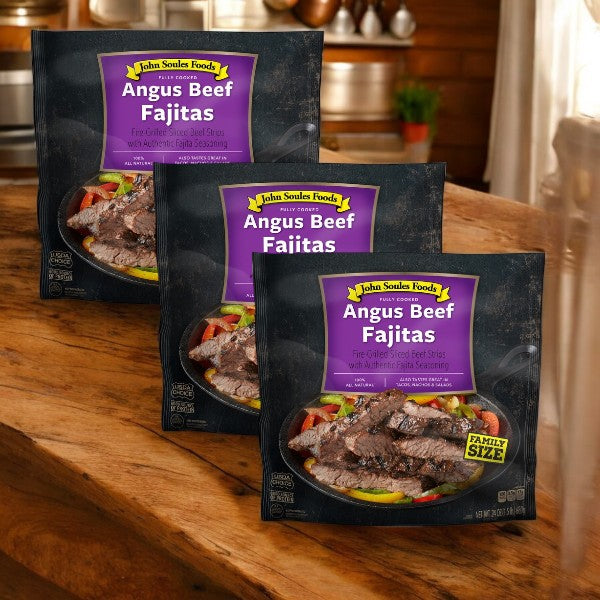 Three packages of John Soules Foods Fully Cooked Angus Beef Fajitas (24 oz, - 3 Cases) are elegantly displayed on a wooden surface in a cozy kitchen setting.