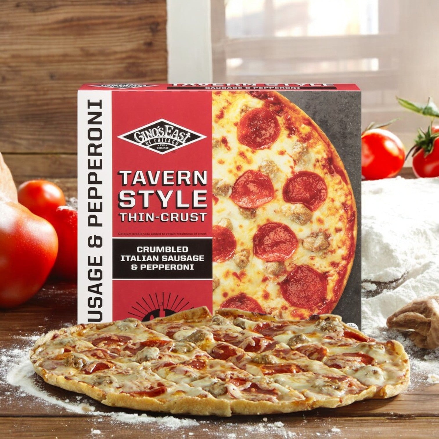 A package of Gino's East Pizza Thin Crust Tavern Style Sausage & Pepperoni, 25 oz, is shown next to the cooked pizza on a floured surface with fresh tomatoes in the background.