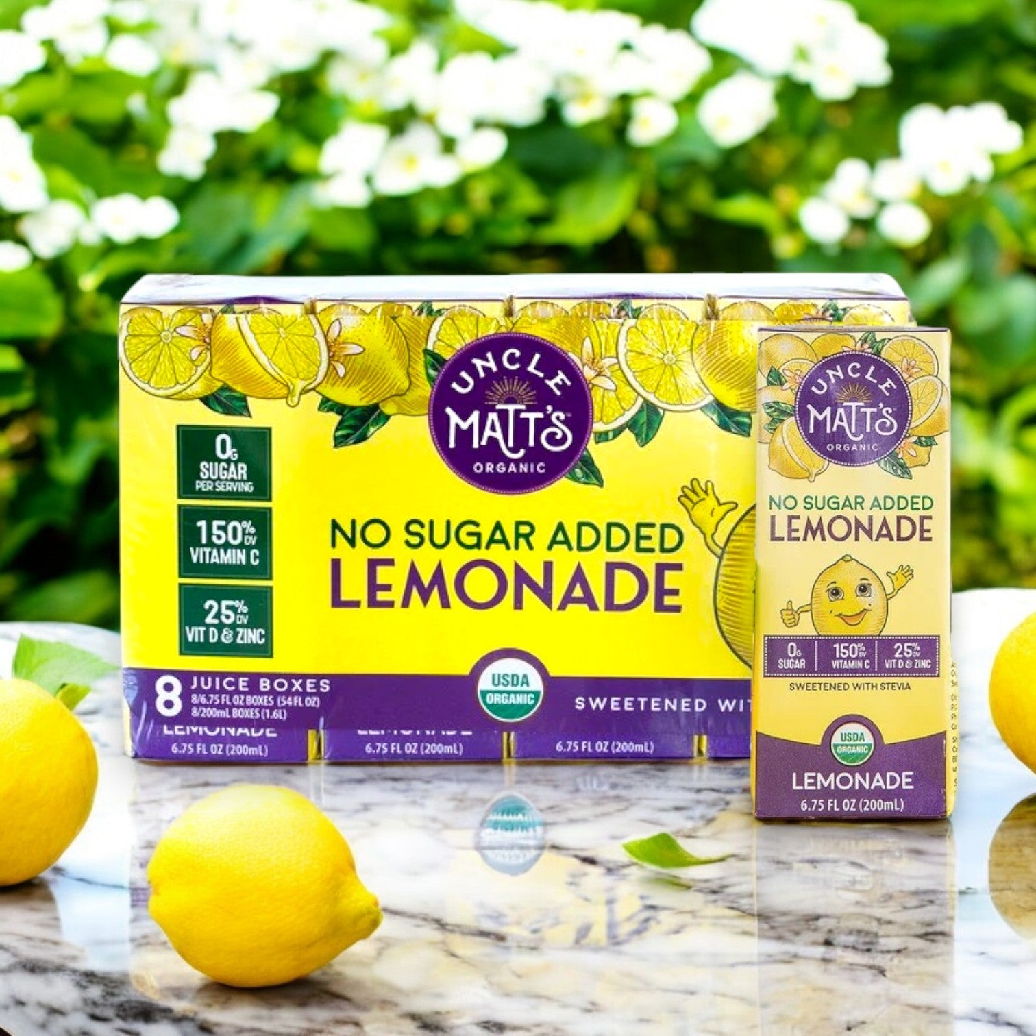 An 8-pack of Uncle Matt's Organic No Sugar Added Lemonade Juice Boxes sits on a marble surface with lemons and greenery in the background, highlighting its immune support benefits.