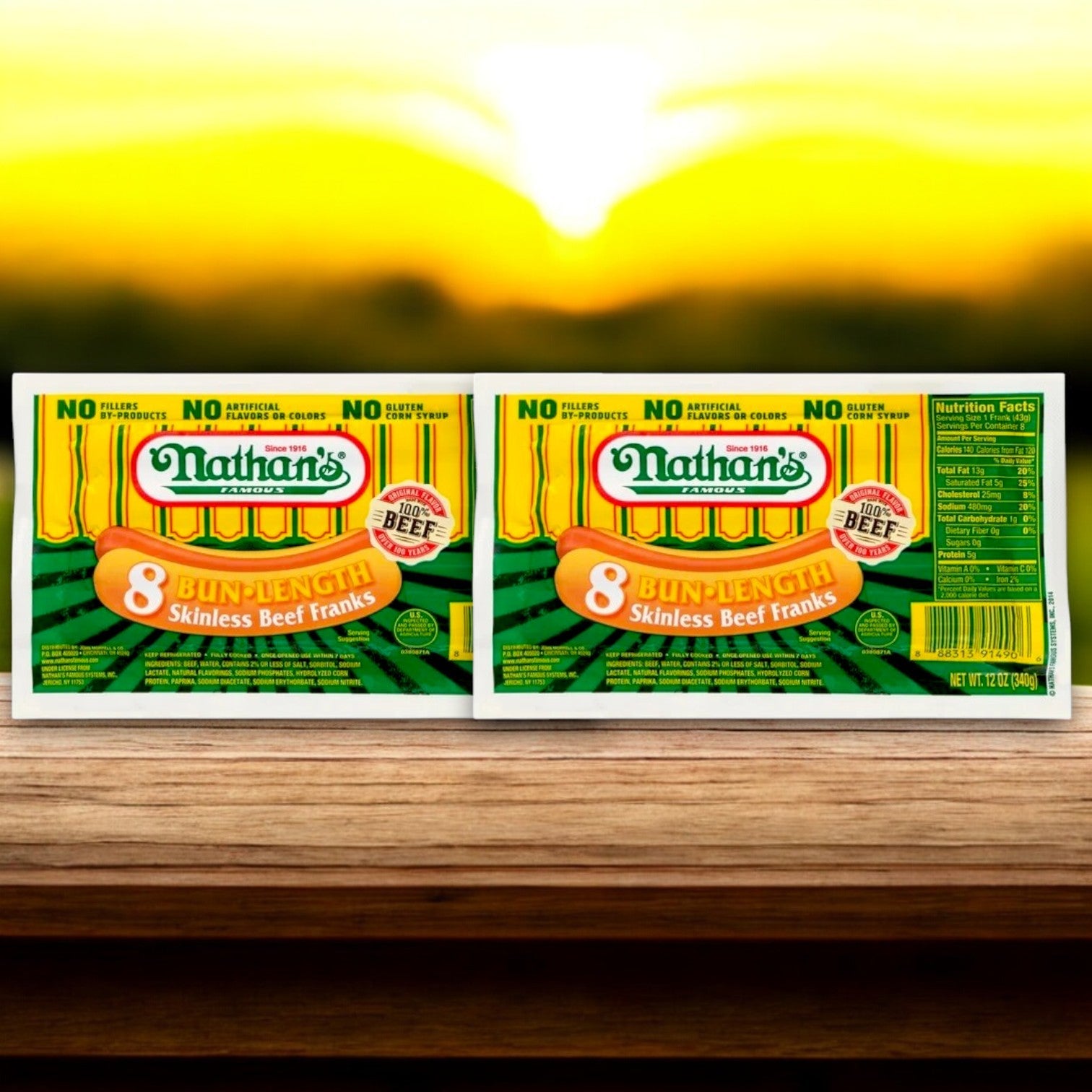 Two packs of Nathan's Bundle – 16 Count Hot Dogs and 16 Buns sit on a wooden surface, bathed in the warm glow of the setting sun, promising a mouthwatering meal.
