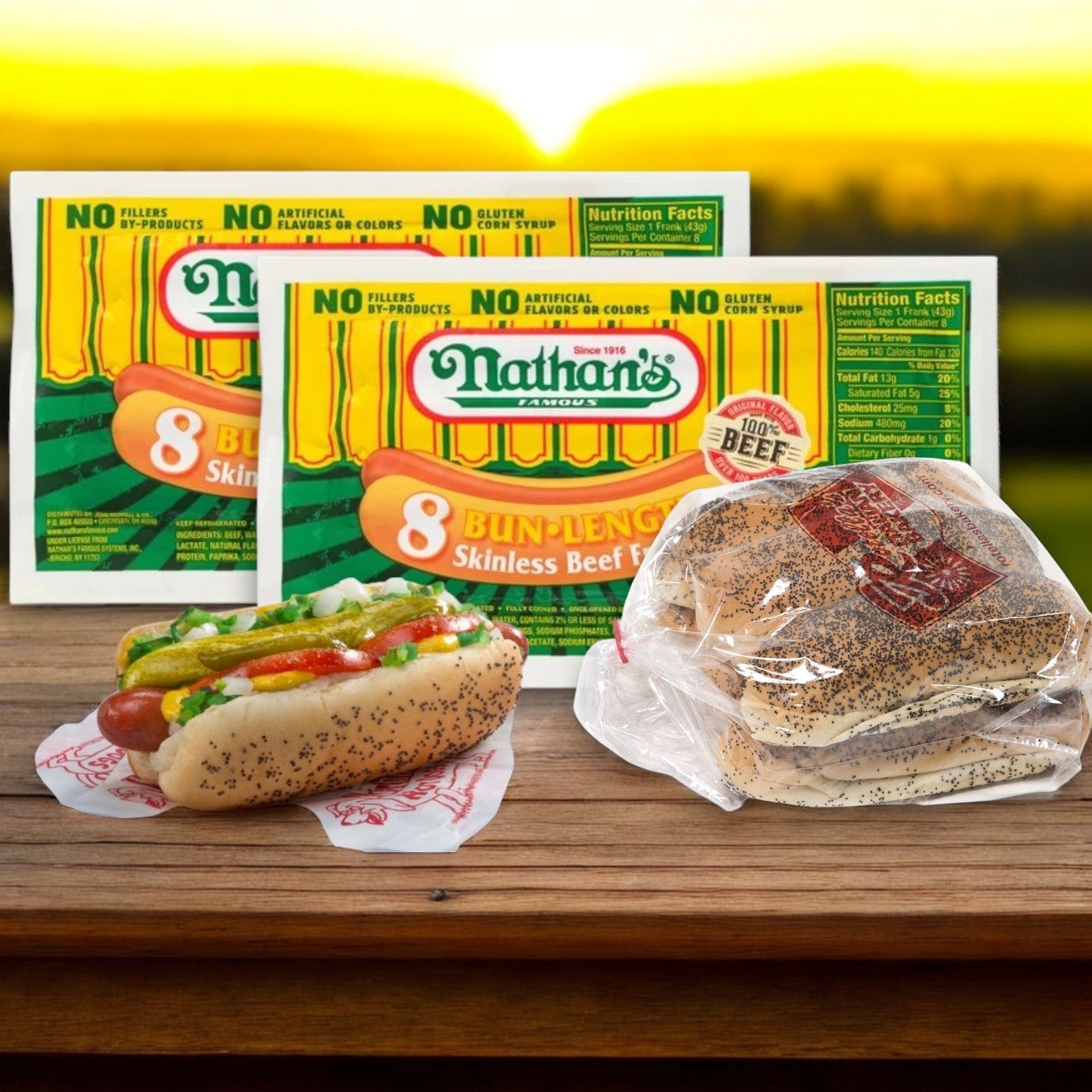 Nathan's Famous Bundle – 16 Count Hot Dogs and 16 Buns!! are beautifully displayed on a table with two boxed packages, a wrapped bun pack, and a perfectly dressed hot dog. The scene glows under the sunset backdrop, highlighted with tasty poppy seed buns.