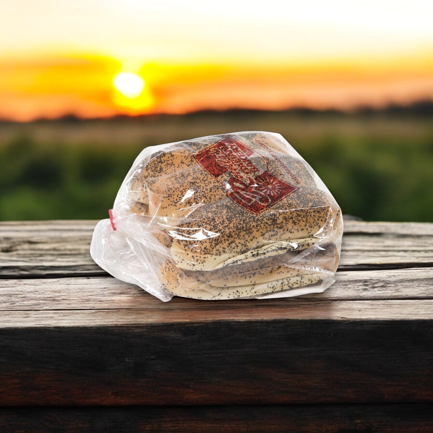 A sealed bag of Nathan's Bundle – 16 Count Angus Beef Hot Dogs & 16 Hot Dog Buns rests on a wooden table, beautifully set against a sunset and grassy field backdrop.