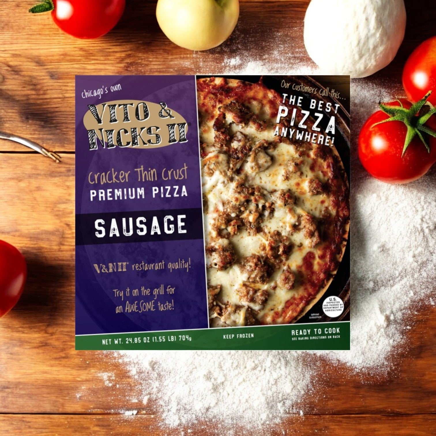 A box of Vito & Nick's II Cracker Thin Crust Sausage Pizza, 24.85 oz, sits on a flour-dusted wooden surface, surrounded by vibrant red bell peppers, a juicy tomato, and a fresh onion.