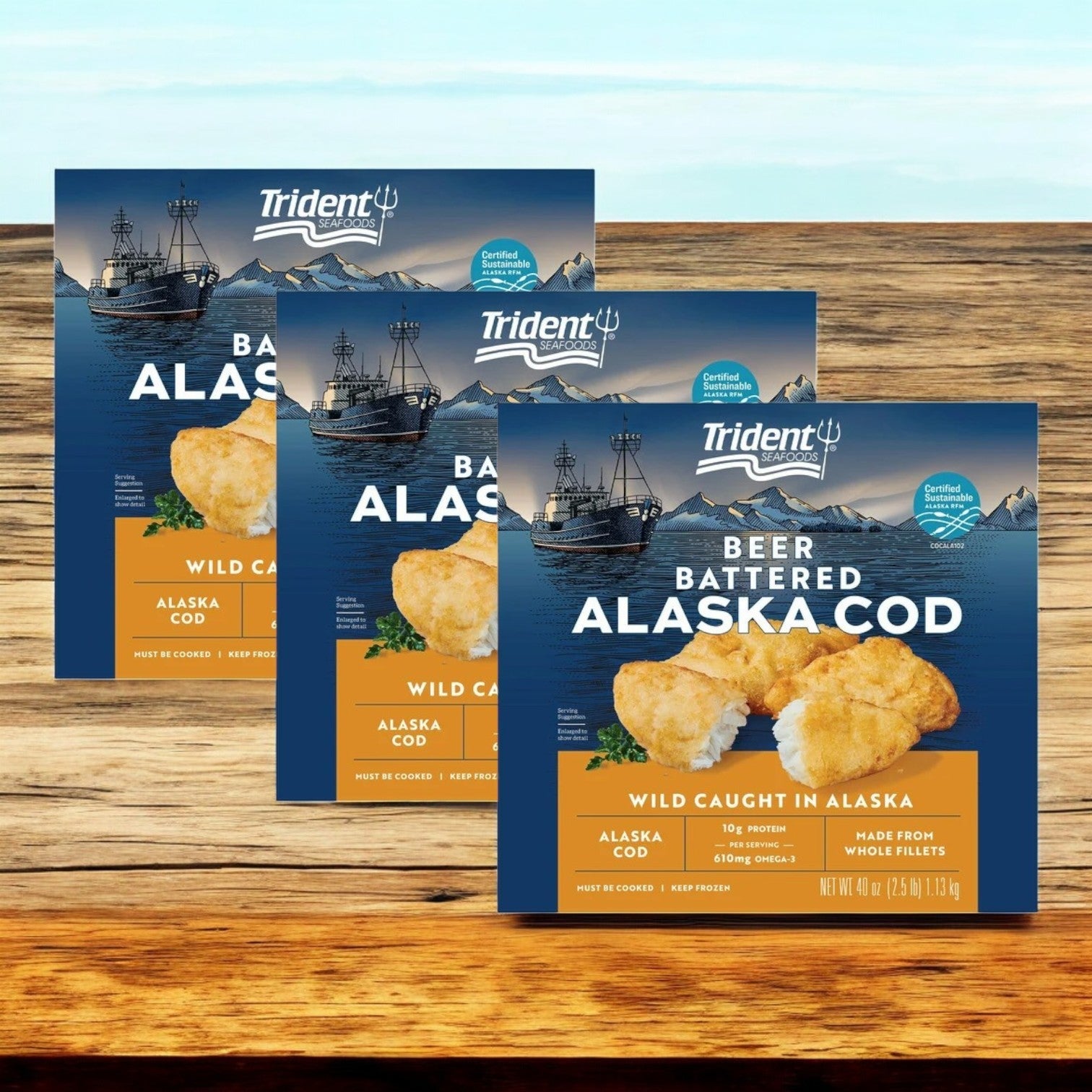 Three boxes of Trident Seafoods Wild Alaskan Beer Battered Cod (7.5 lbs), a wild-caught Alaskan cod product, display images of fishing boats and snow-capped mountains.