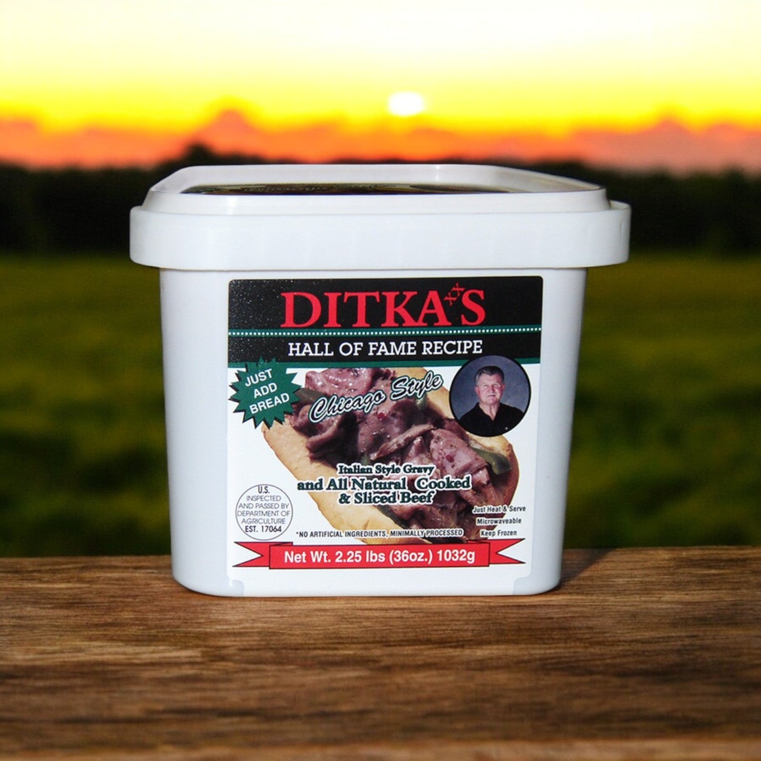 A white tub labeled "Ditka’s Italian Beef Sandwich Kit with Turano Rolls & Marconi Giardiniera" by Vienna Beef sits on a wooden surface against a sunset, perfect for preparing classic Chicago Italian Beef sandwiches.