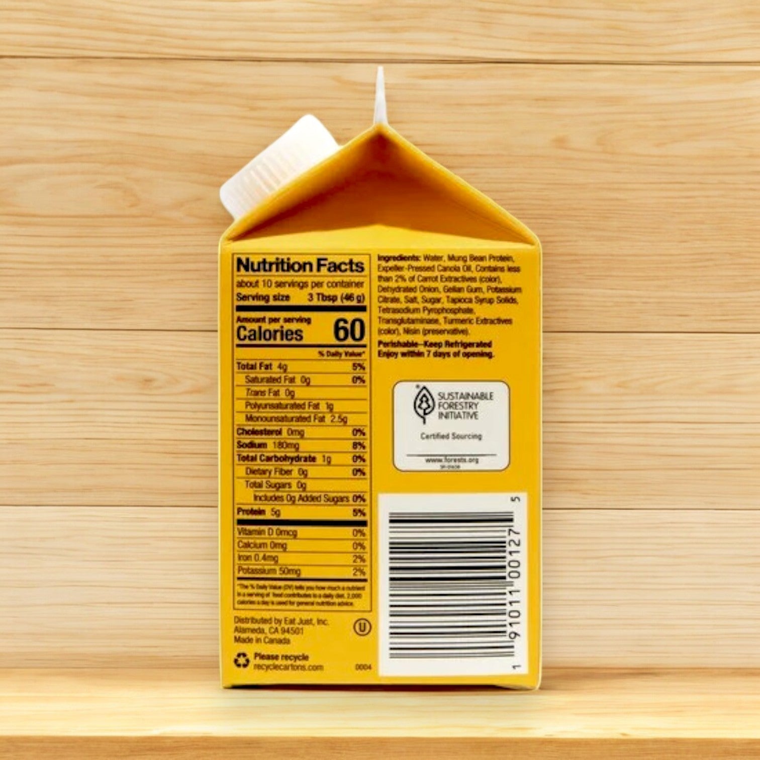 Just Egg Plant-Based Egg (16 oz) carton against a wooden background displays nutrition facts, ingredients, and sustainability certification—a superb plant-based option from Just Egg that's also cholesterol-free.