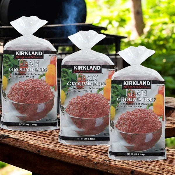 Three packages of Kirkland Signature Lean Ground Beef sit on a wooden table. Each 5-pound pack contains five 1-pound portions and features a 91% lean, 9% fat composition, ideal for meal prepping. Perfect for those seeking premium-quality beef that's both convenient and health-conscious.