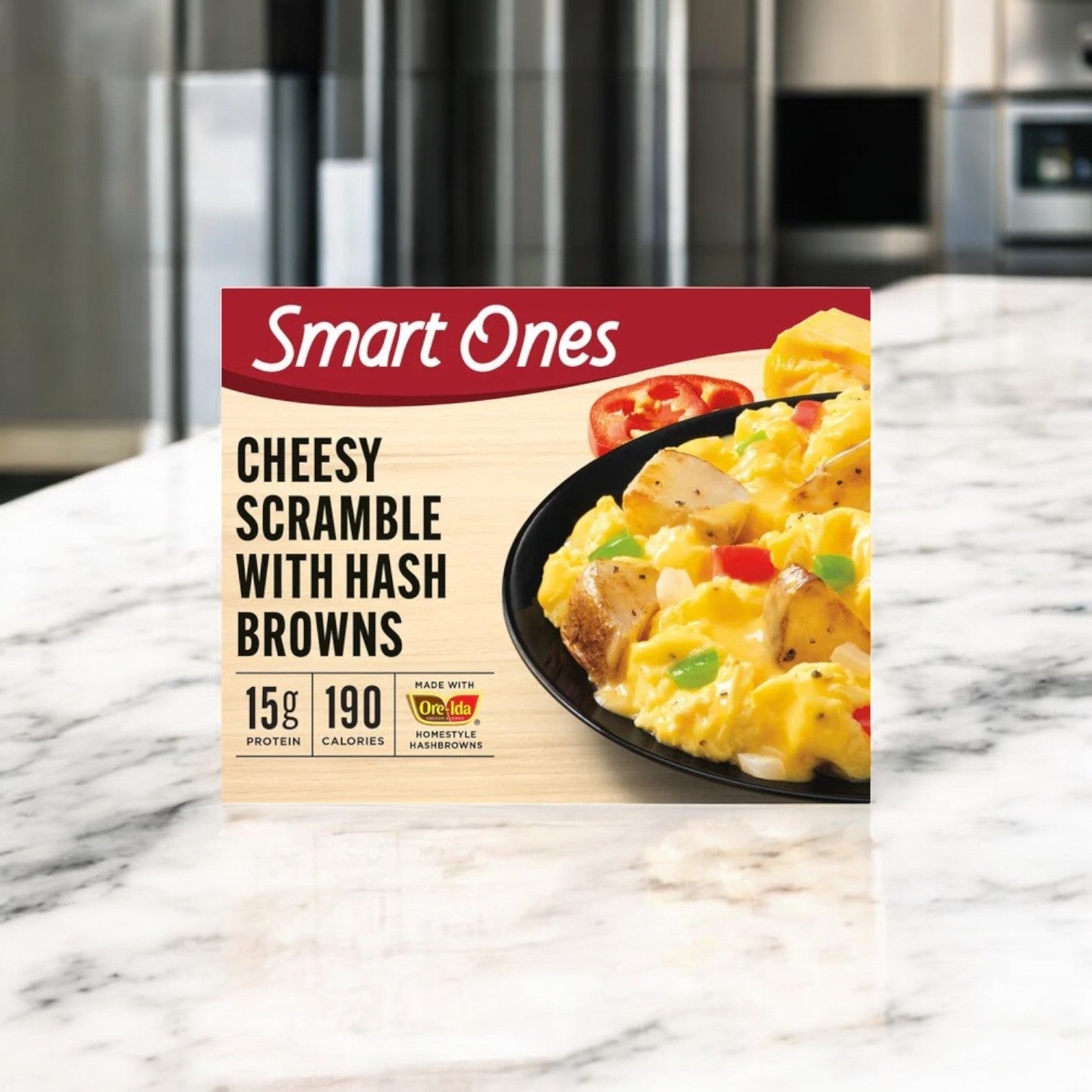 The Smart Ones Hash Browns, Eggs & Cheddar with Monterey Jack & Mozzarella Cheeses Frozen Meal, offering 15g protein and 190 calories, sits on a marble countertop; this microwaveable delight complements any meal lineup like the savory Ziti Marinara.