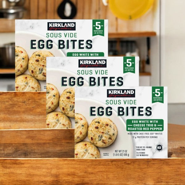 Three boxes of Kirkland Signature Egg Bites, each with ten servings of egg whites, cheese trio, and roasted red peppers, are displayed on a wooden surface.