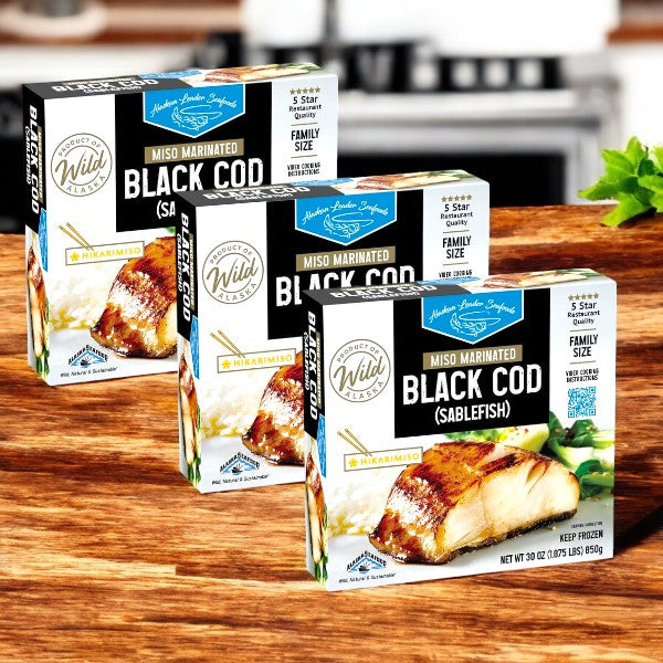Three packages of Alaskan Leader Seafoods Black Cod, Miso Marinated, 30 oz, sit on a wooden surface, showcasing their family-size labels and brand details.