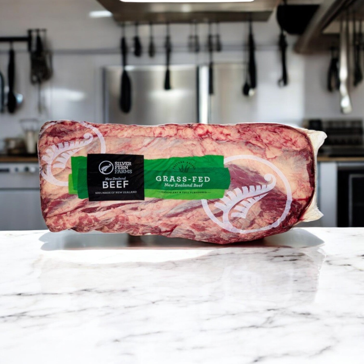 A vacuum-sealed package of Silver Fern Farms Halal Beef Boneless Ribeye rests on a marble countertop in a modern kitchen setting.