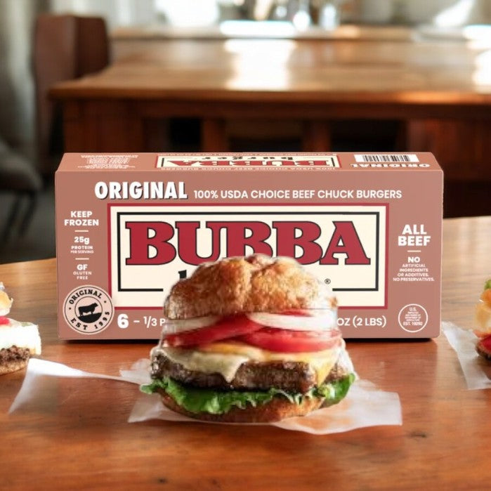 A box of Bubba Burger Original 6 Count Frozen patties is on the kitchen table, while a delicious burger with lettuce, tomato, cheese, and onions takes center stage. Made with juicy USDA Choice Angus beef, these burgers from Bubba promise a satisfying meal every time.