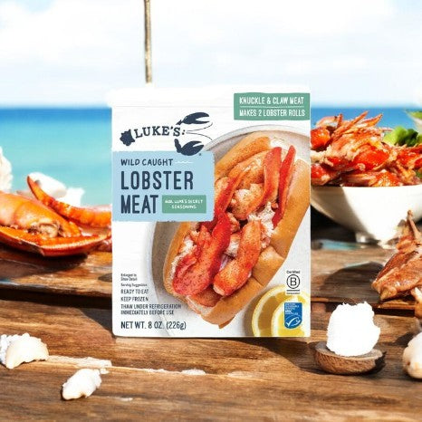 A pack of Easy Lunches' Luke's Lobster Wild-Caught Lobster Meat with Luke's Secret Seasoning (8 oz) is shown next to lobster rolls and whole lobsters in the background.