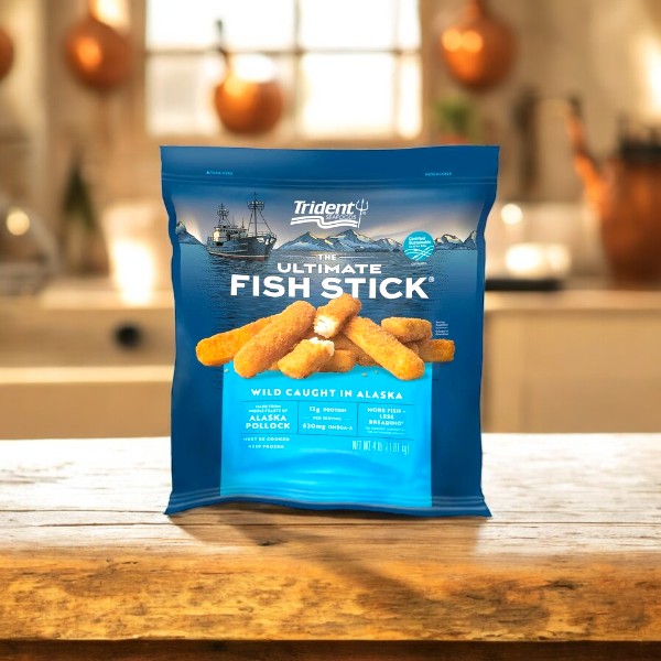 In a rustic kitchen, a 4 lb package of Trident Seafoods Panko Breaded Wild Caught Alaska Pollock Fish Sticks, branded as "The Ultimate Fish Stick," rests on a wooden table.