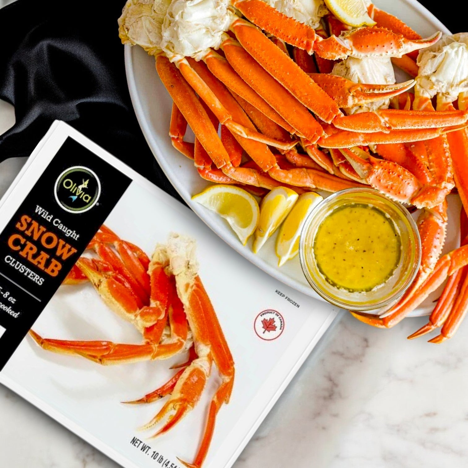 A premium seafood plate showcases IFC Seafood's Olivia Wild Caught Snow Crab Clusters, Fully Cooked, 10 lbs, garnished with lemon wedges and accompanied by a savory dipping sauce.