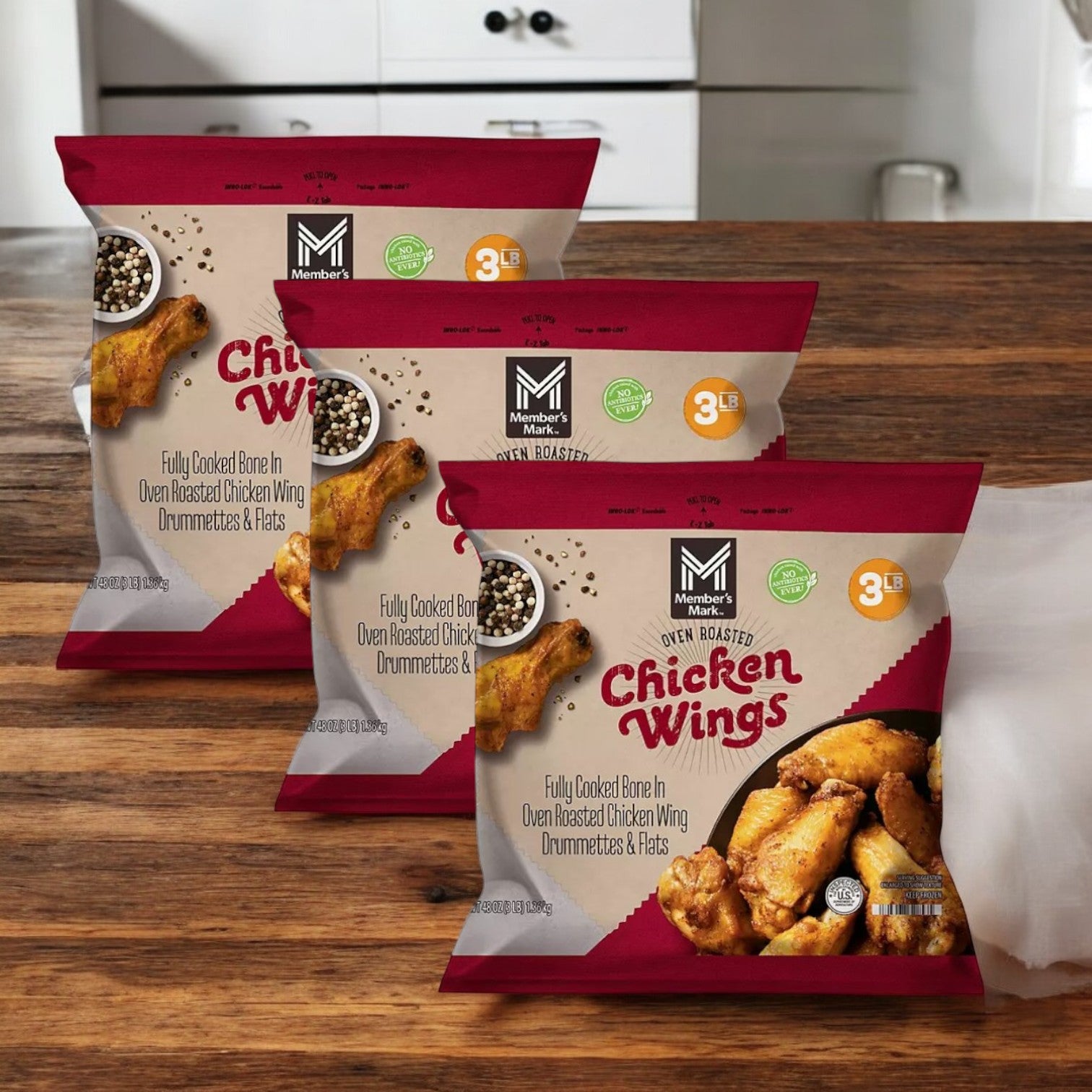 Three 3-pound bags of Member's Mark Oven Roasted Chicken Wings are displayed on a wooden surface; totaling 9 pounds, they offer a healthier alternative with an irresistible crispy exterior.