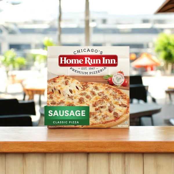 A Home Run Inn Variety Pack box, containing 4 pizzas including sausage classic, sits on a wooden table outdoors with a blurred background. Topped with savory sausage and mozzarella, this pizza is from the popular Home Run Inn brand.