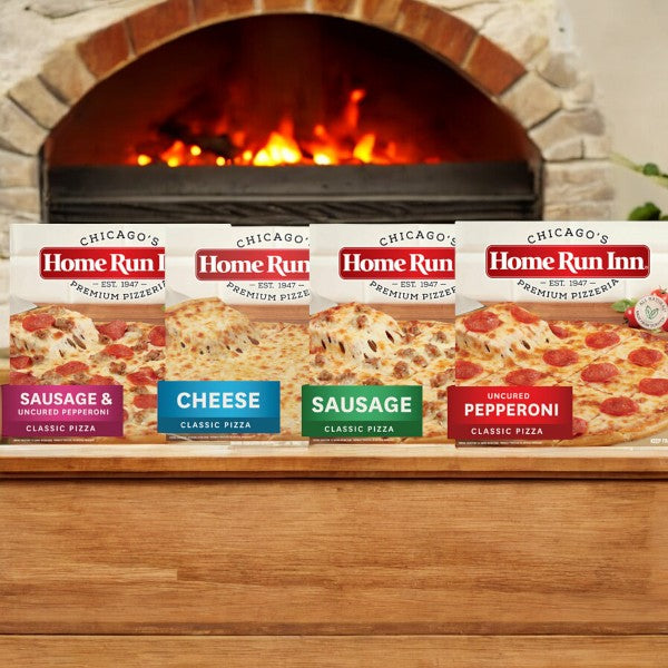 Four Home Run Inn Variety Pack pizza boxes are displayed in front of a lit oven, featuring flavors like Sausage & Uncured Pepperoni, Cheese with rich mozzarella, Sausage, and Uncured Pepperoni.