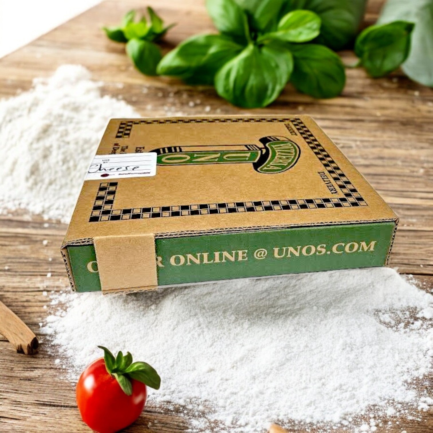 A wood surface holds a "Pizzeria Uno" pizza box amid flour, a cherry tomato, cinnamon sticks, and basil leaves—suggesting the delicious Pizzeria Uno Deep Dish Small Cheese Pizza inside, oozing with rich mozzarella.