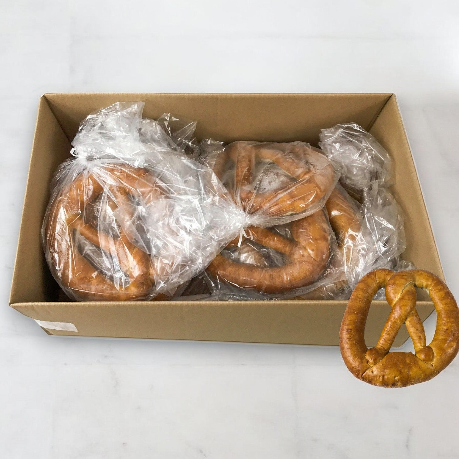 The Milwaukee Pretzel Company Bavarian Soft Pretzels (10 Count, 16 oz each) box contains authentic large pretzels, each individually wrapped in clear bags, with one showcased outside the box.