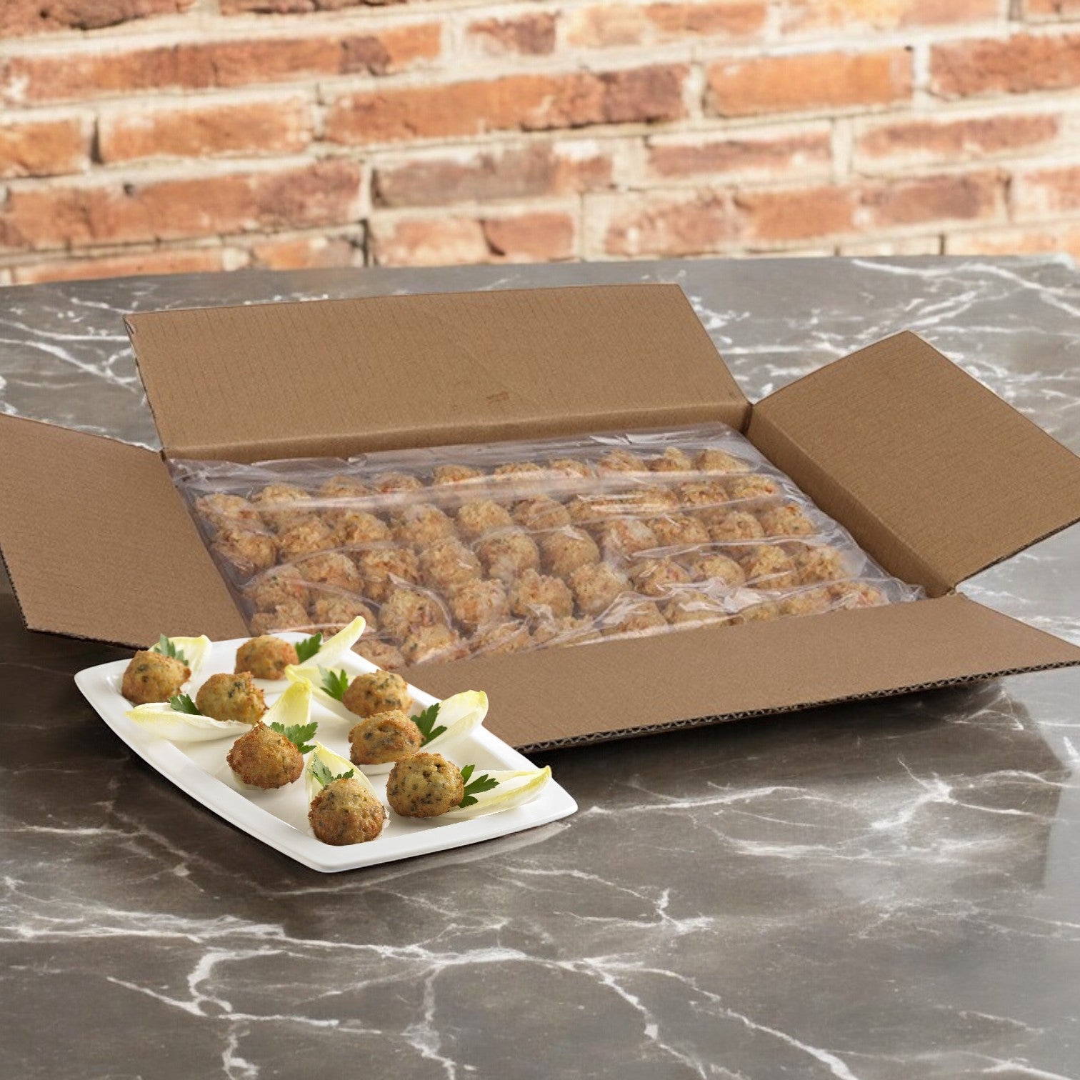 An open box of Phillips Foods Crab Cake Mini Claw, .75 oz., with 100 pieces, is beside a plate displaying a few cooked crab cakes on a marble surface.