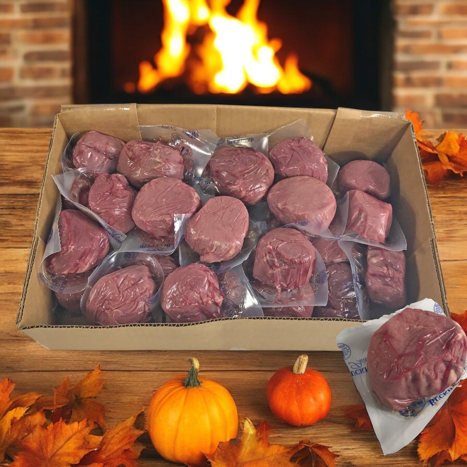 A box of Buckhead Pride/Newport Pride, 1 Case Steak Filet Center-Cut Butchers Preferred 28-6oz Steaks, rests on a wooden table with small pumpkins and autumn leaves near a fireplace. The steaks' superior tenderness ensures a buttery-smooth texture with every bite.