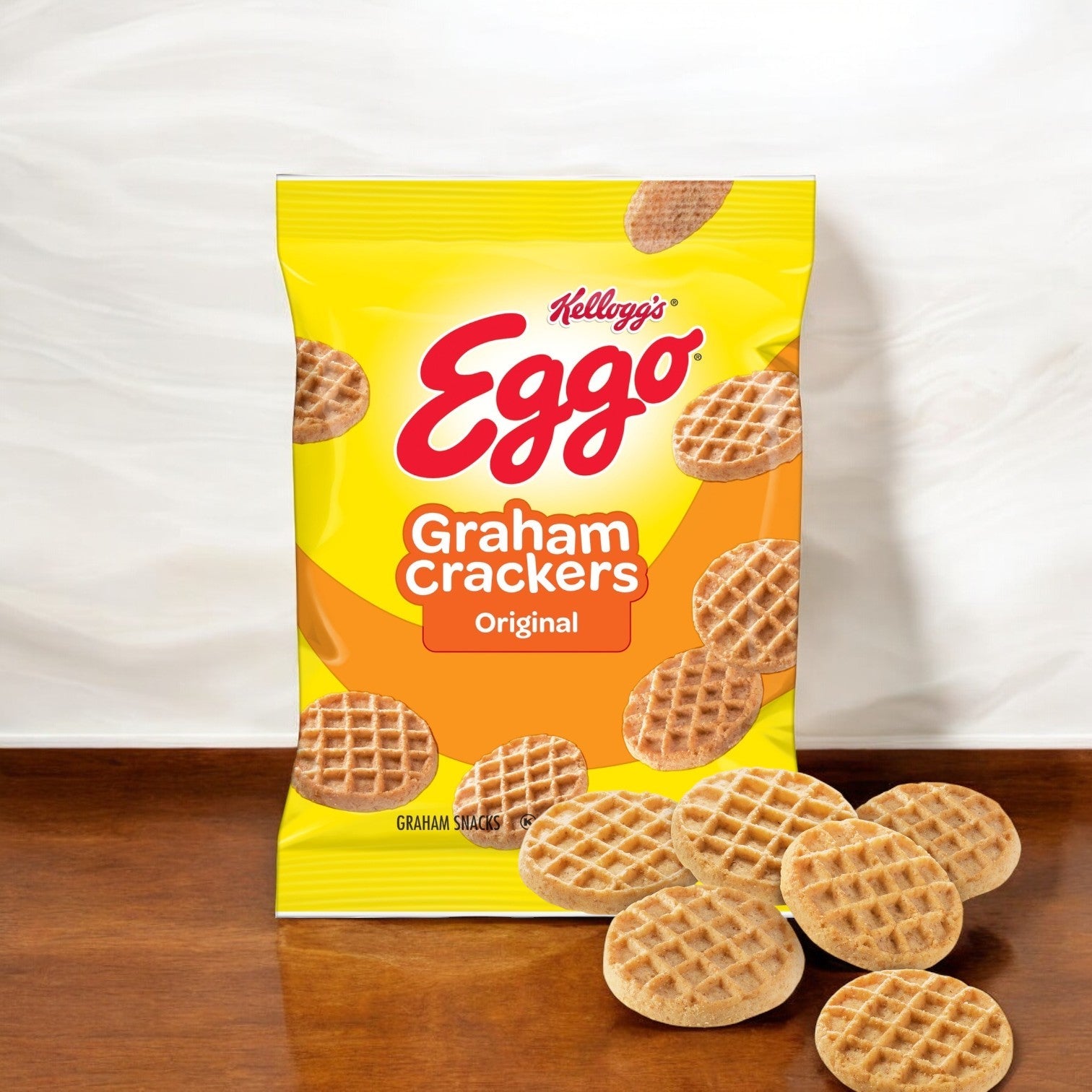 A case of Kellogg's Eggo Waffle's Graham Crackers sits on a wooden surface, surrounded by scattered crackers, offering a delightful touch of whole grain goodness.