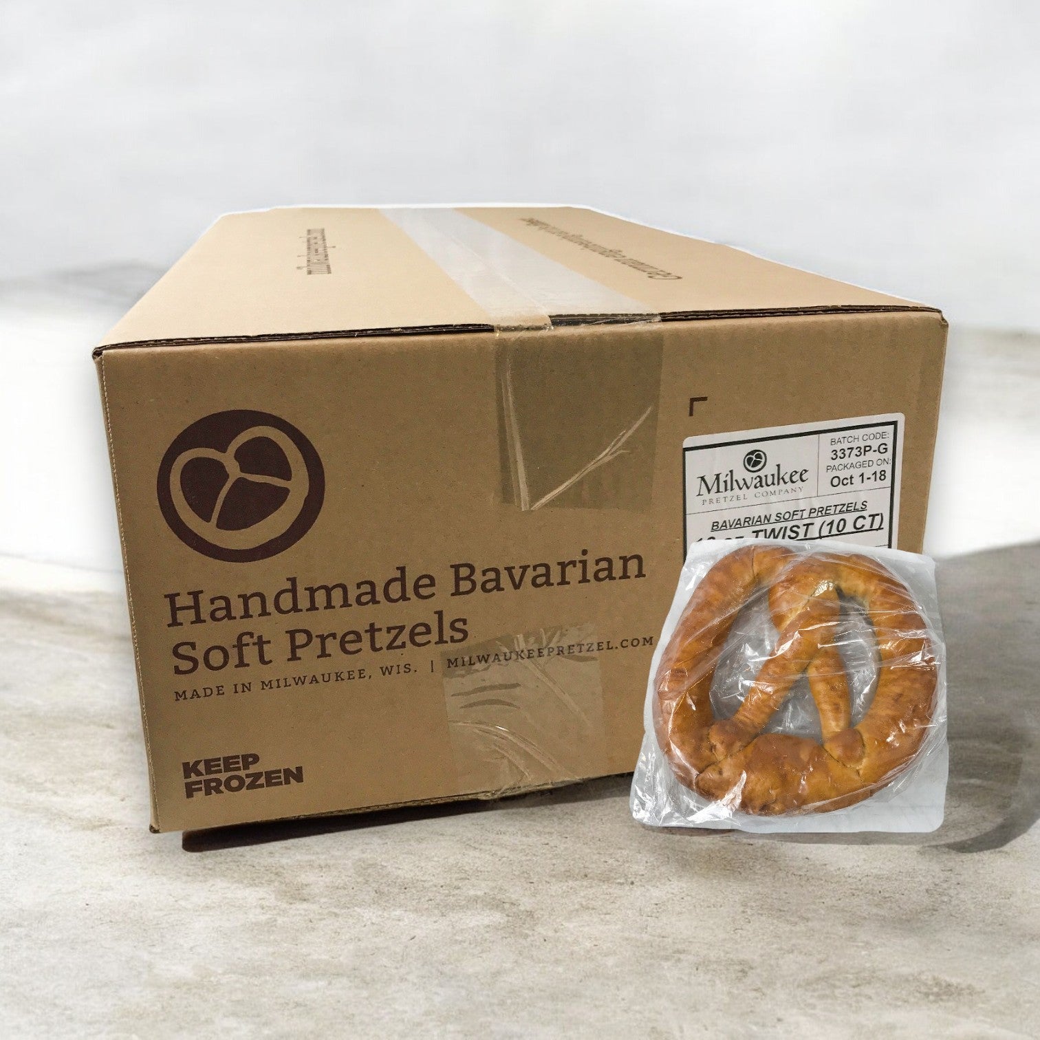 A package of Milwaukee Pretzel Company Bavarian Soft Pretzels (10 Count, 16 oz each) is beside a pretzel on a cement floor.