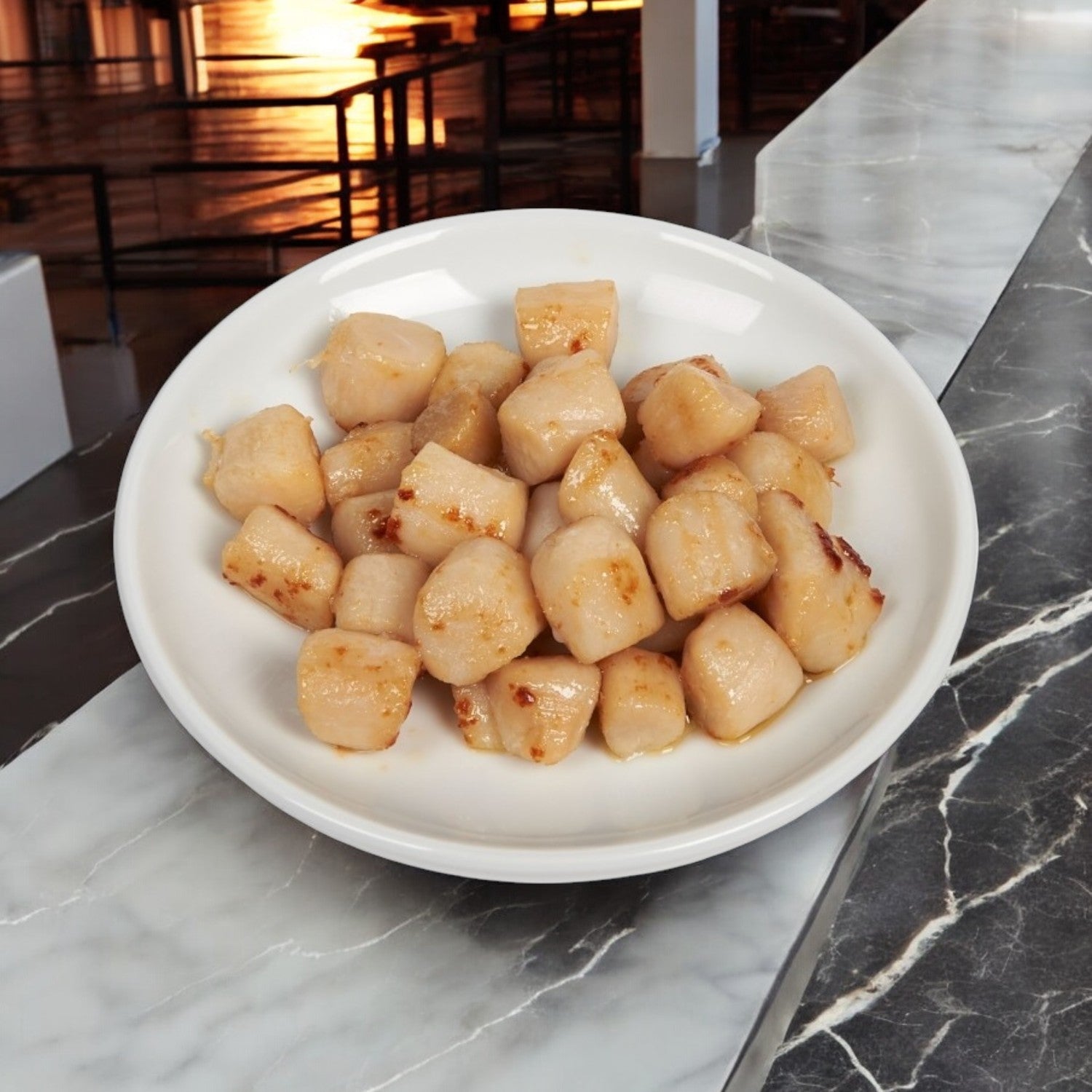 A white plate elegantly displays perfectly cooked scallops from Portico Classic Seafood's Scallop IQF Dry 60-80 Count Imported, arranged on a marble surface.