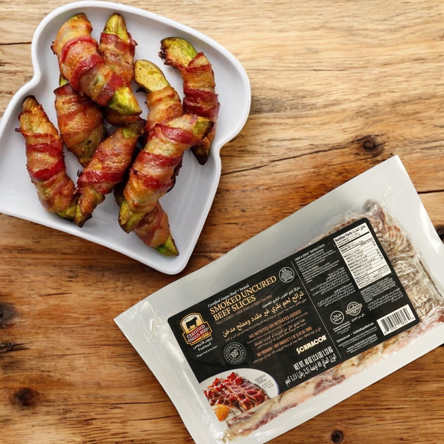 A heart-shaped plate with bacon-wrapped avocado slices rests beside a package of Certified Angus Beef Bacon Beef Halal Schmacon on a wooden surface.