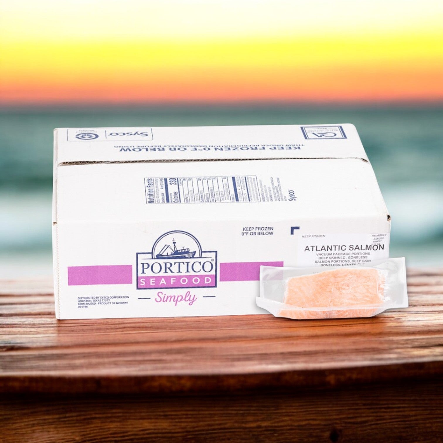 A wooden table holds a cardboard box labeled "Portico Classic Seafood," containing Norwegian Atlantic Salmon Portions, Skinless, 4 oz. Rich in Omega-3 fatty acids, this product complements the background ocean sunset.