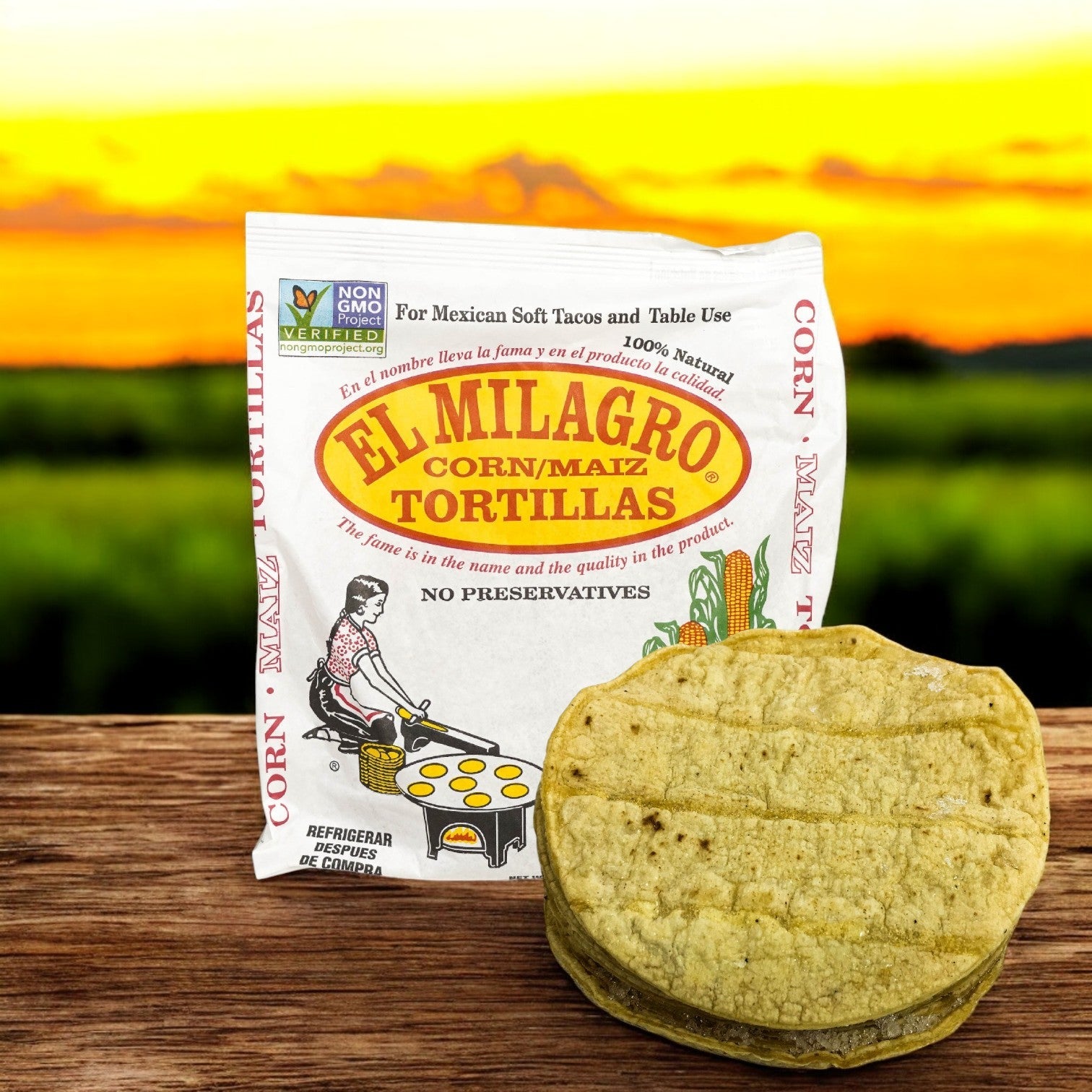 El Milagro Corn Tortillas, Yellow 6" One Dozen, a staple of Mexican cuisine, is shown against a blurred outdoor background. A stack of these premium tortillas sits in front of the package, inviting you to enjoy their authentic taste.