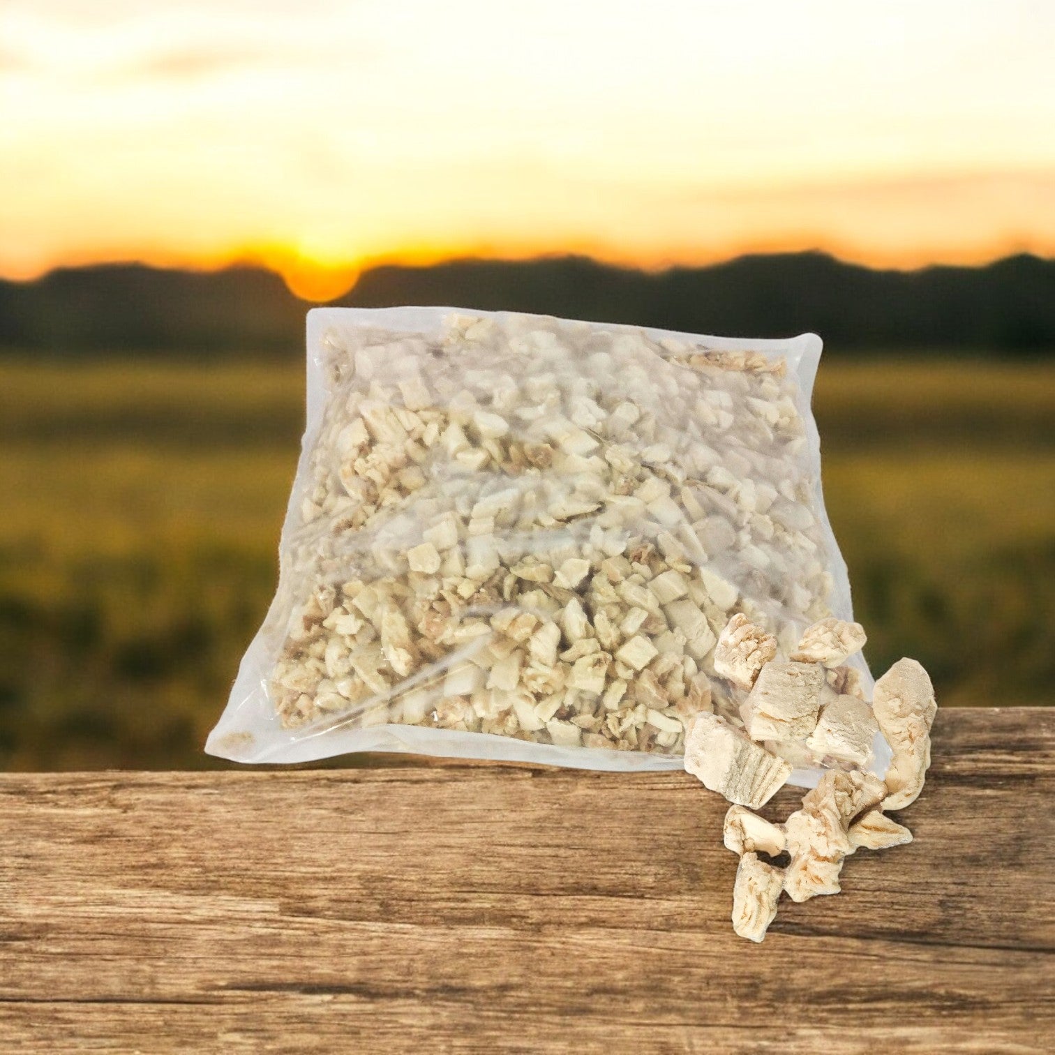 A sealed plastic bag of dried mushrooms is on a wooden surface, with a few pieces scattered around. The sunset casts gentle hues over a blurred landscape in the background. Ideal when paired with Sysco's Diced White Chicken Meat Low Sodium – 2/5 LB for a gourmet experience.