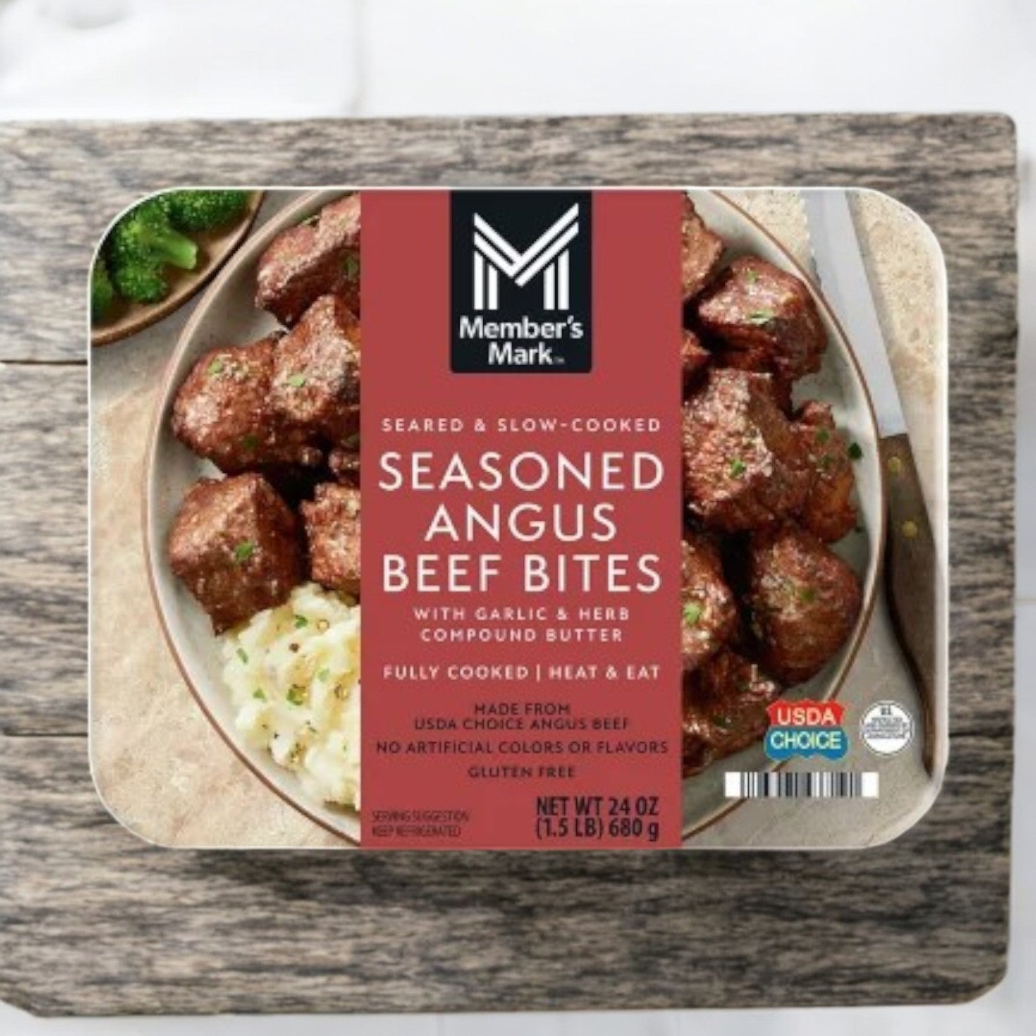Member's Mark Seasoned Angus Beef Bites, featuring garlic and herb compound butter, are showcased on a wooden surface with the product name, USDA Choice label, and a weight of 1.5 lbs (24 oz).