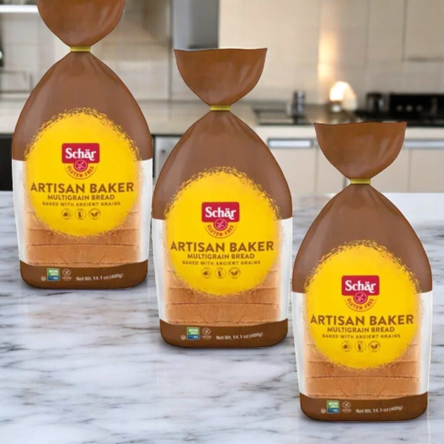 Three packs of Schär Artisan Baker Multigrain Bread, gluten-free and high in fiber, are showcased on a marble kitchen countertop.