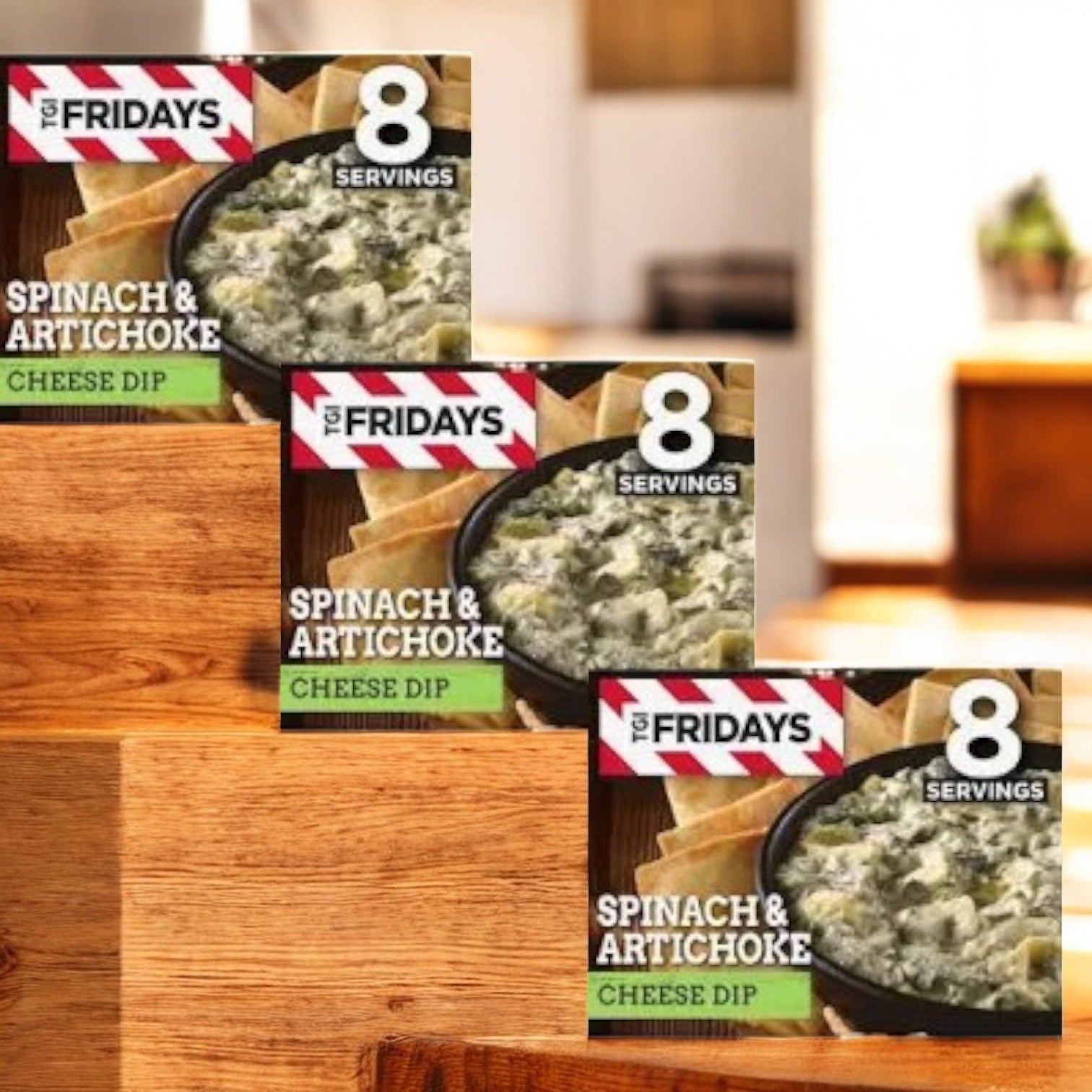Three boxes of TGI Fridays Spinach & Artichoke Cheese Dip Frozen Snacks & Appetizers are stacked on a table, each offering 8 servings. The blurred kitchen background highlights the charm of these delightful snacks from TGI Fridays.