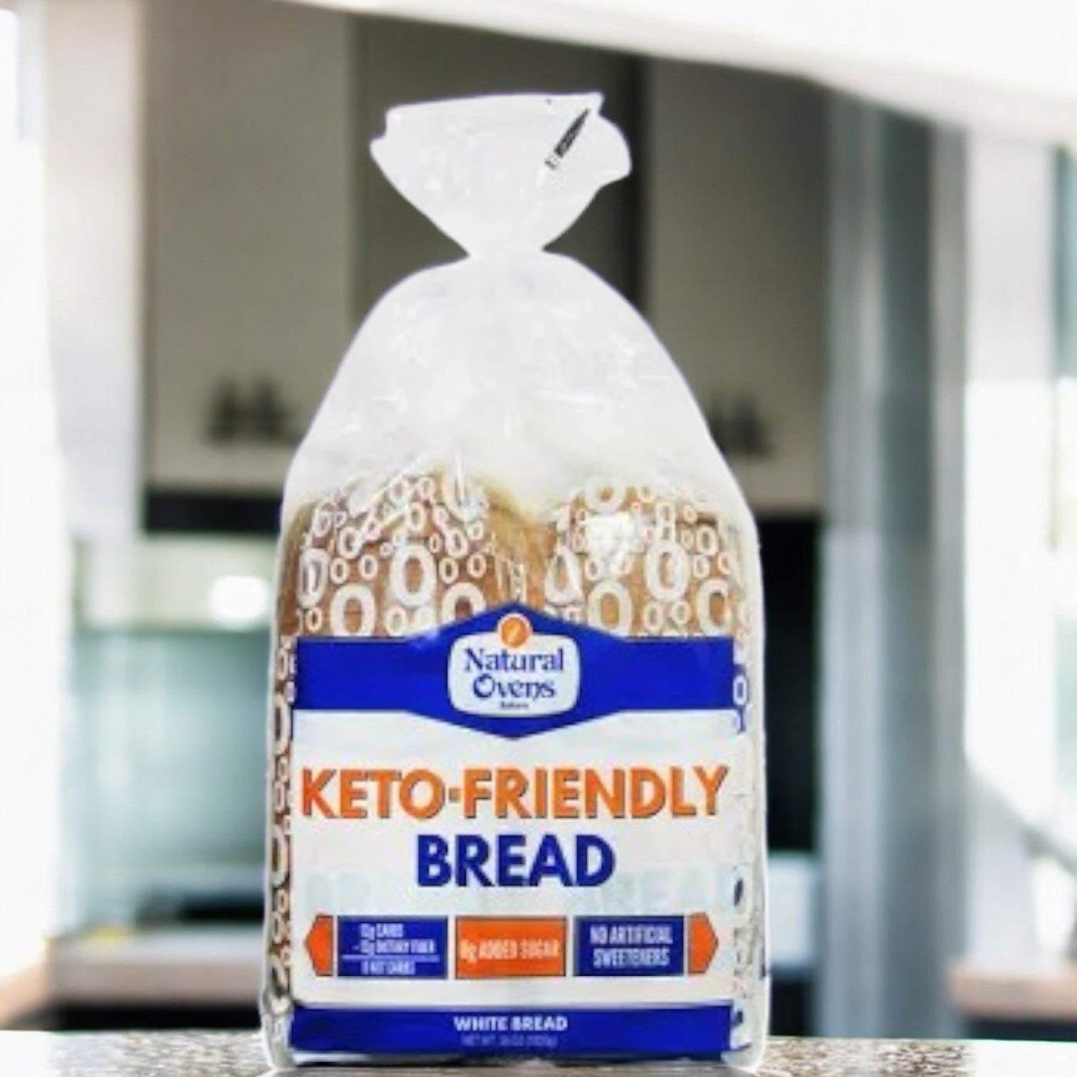 A package of Natural Oven's Keto Friendly Bread-1 Count sits on a kitchen counter with the label visible—ideal for those on a keto diet.
