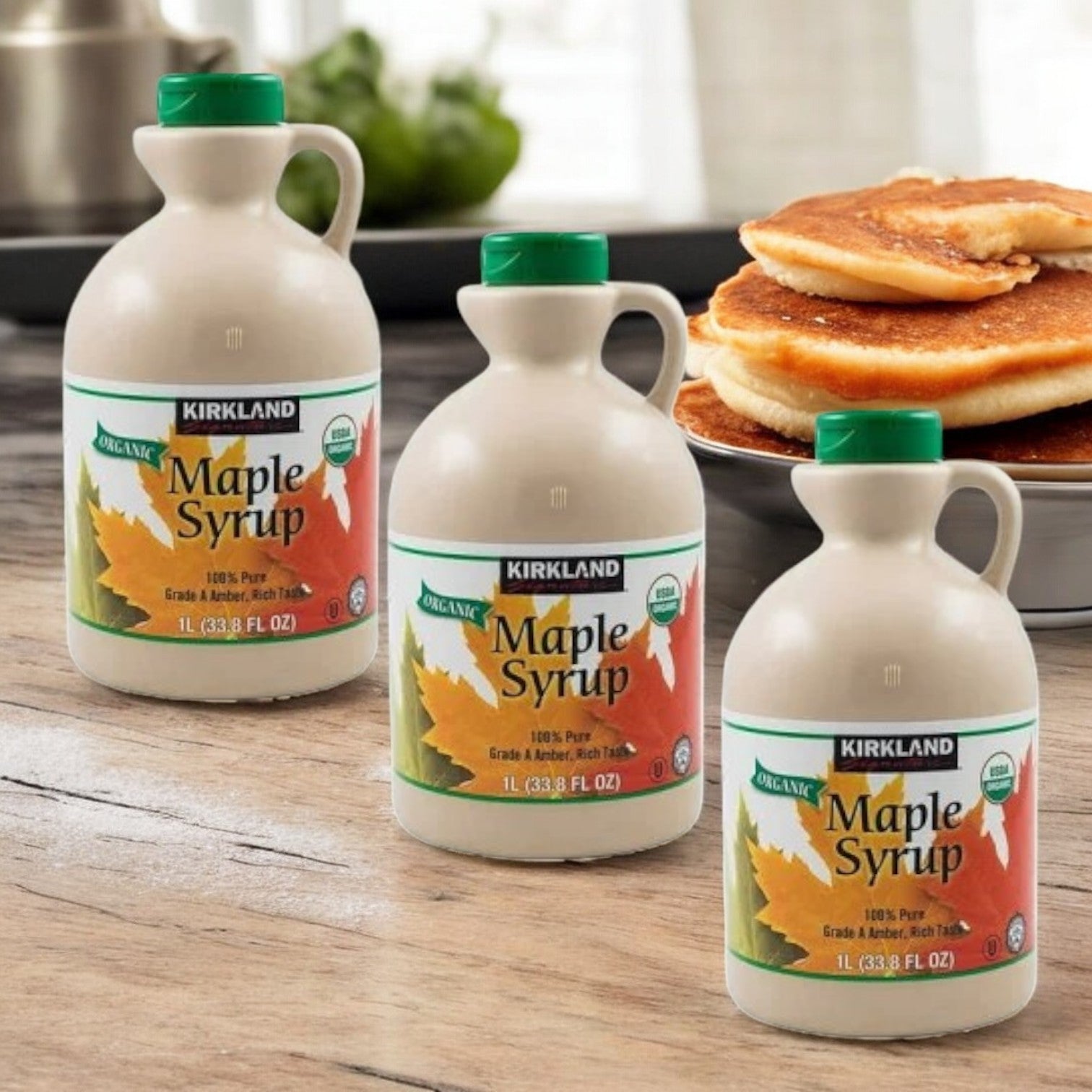 Three bottles of Kirkland Signature Organic Pure Maple Syrup are displayed on a wooden table, highlighting their USDA-Certified Organic label, with a plate of pancakes in the background.
