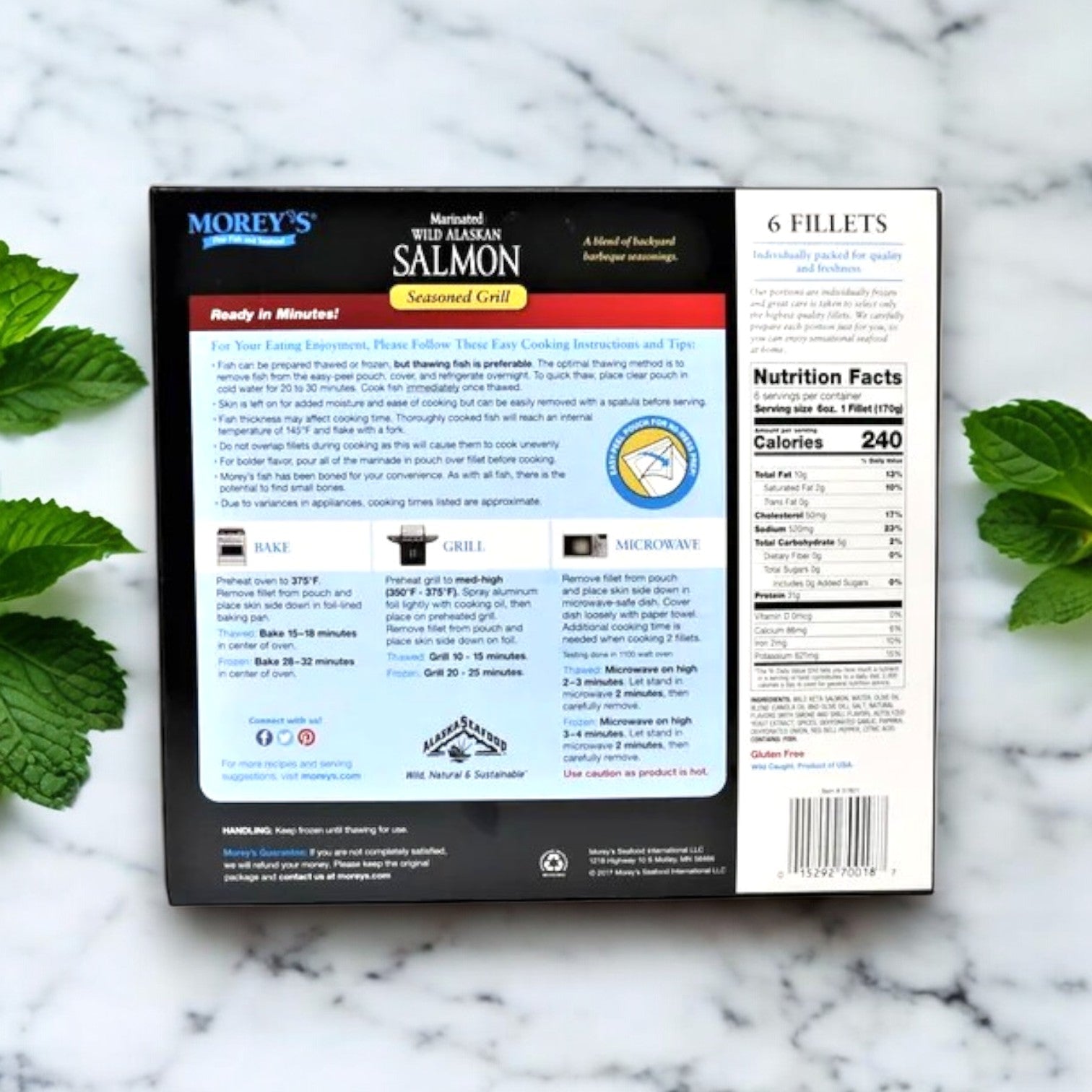 Back of a Morey's Fine Fish & Seafood Marinated Wild Alaskan Salmon 6 ct box, showing cooking instructions and nutrition facts, with six premium salmon fillets displayed on marble beside fresh mint leaves.