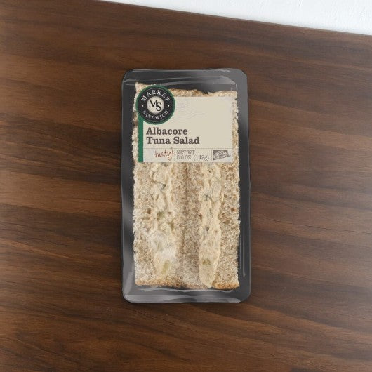 E.A. Sween's Albacore Tuna Salad Sandwich, showcasing lean tuna filling, is displayed on a wooden surface. Sold in a case of 10, it ships frozen with a 30-day shelf life once thawed.