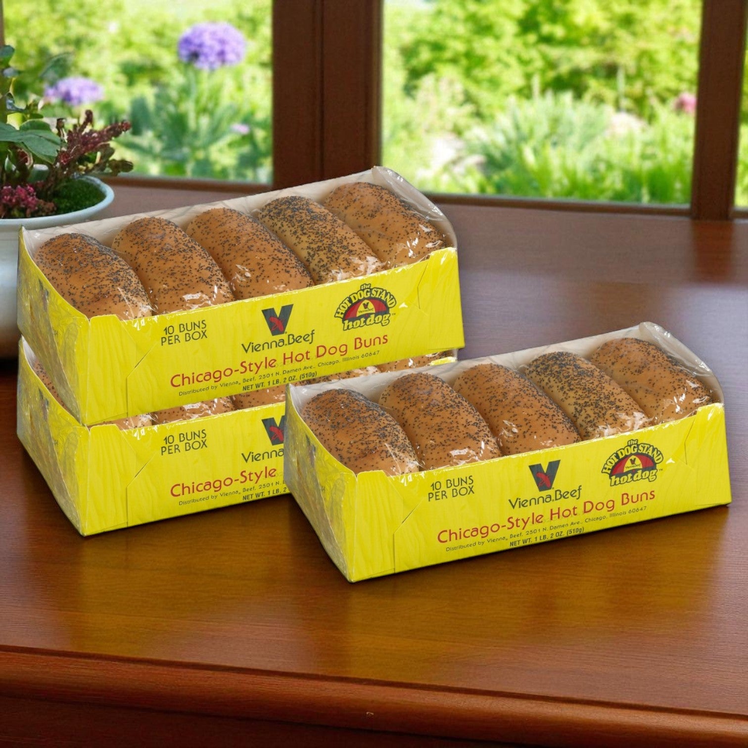 The Vienna Beef Franks & Poppy Seed Bun Combo—featuring 32 franks and 30 authentic Chicago-style buns—sits on a wooden table by a window with lush plants outside, perfect for an iconic hot dog meal.