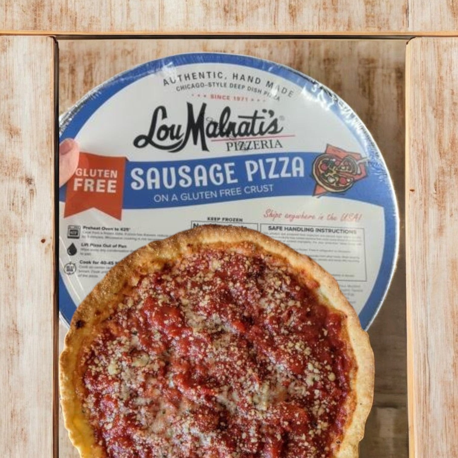 Lou Malnati's Gluten-Free Sausage Deep Dish Pizza, weighing 28.25 oz, is showcased on a wooden table with the packaging in the background.
