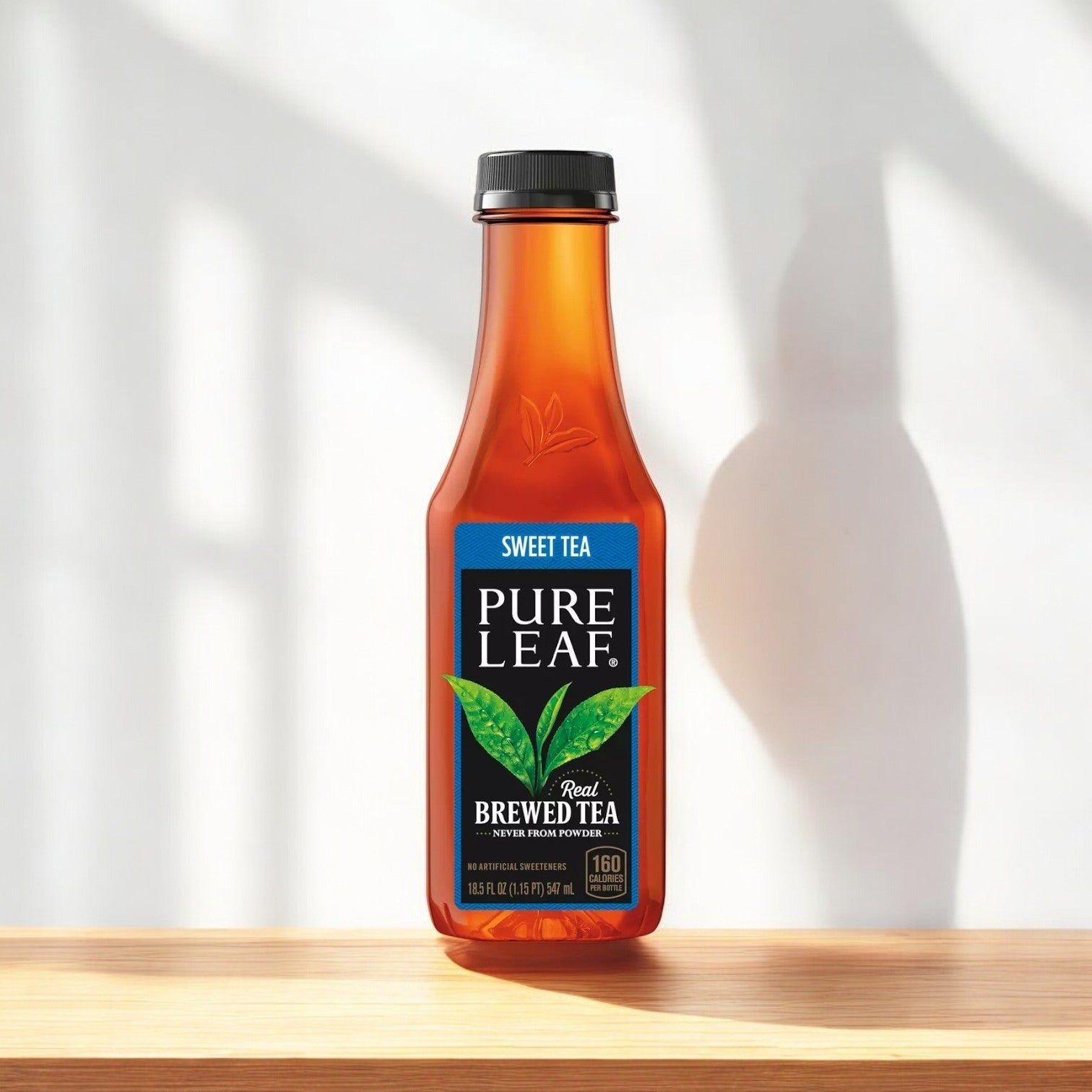 A bottle of Pure Leaf Brewed Tea sits on a wooden surface, casting a shadow. This refreshing unsweetened drink is brewed from real tea leaves, highlighting the quality and taste of Pure Leaf's offerings.