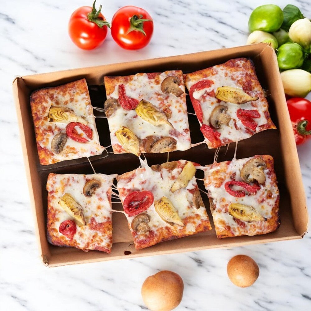 A 23.1 oz. box of Massa Pizza Co. Roasted Veggie Sicilian Bakery Pizza by Massa Pizza, featuring six square slices topped with cheese, mushrooms, artichokes, and red peppers. Fresh tomatoes and green peppers adorn the background on a marble surface, complementing this roasted veggie pizza masterpiece.