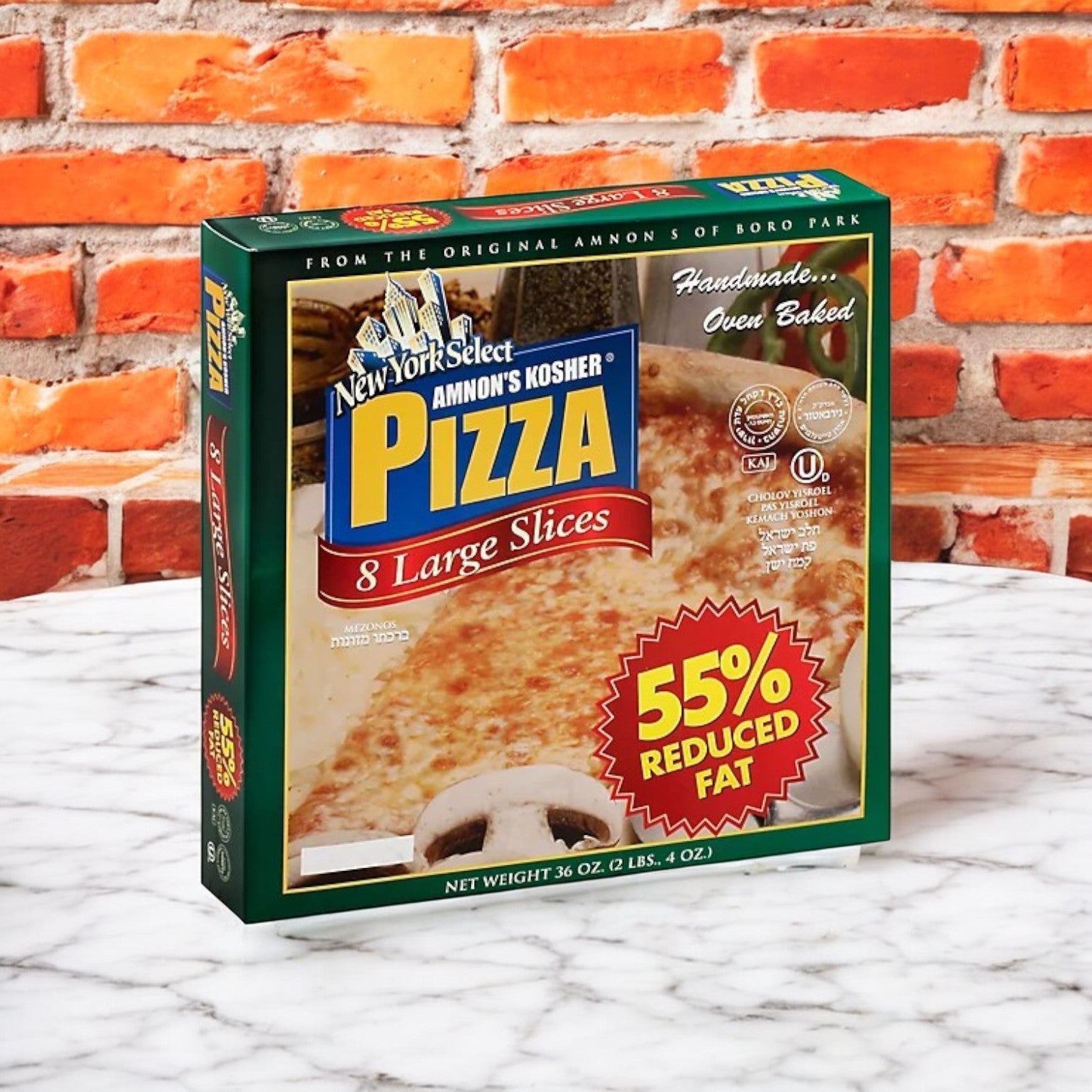 A box of Amnon's Kosher Pizza 55% Reduced Fat Frozen 36 oz. - 3 Count, featuring 8 large slices and a healthier profile, rests on a marble surface in front of a brick wall.