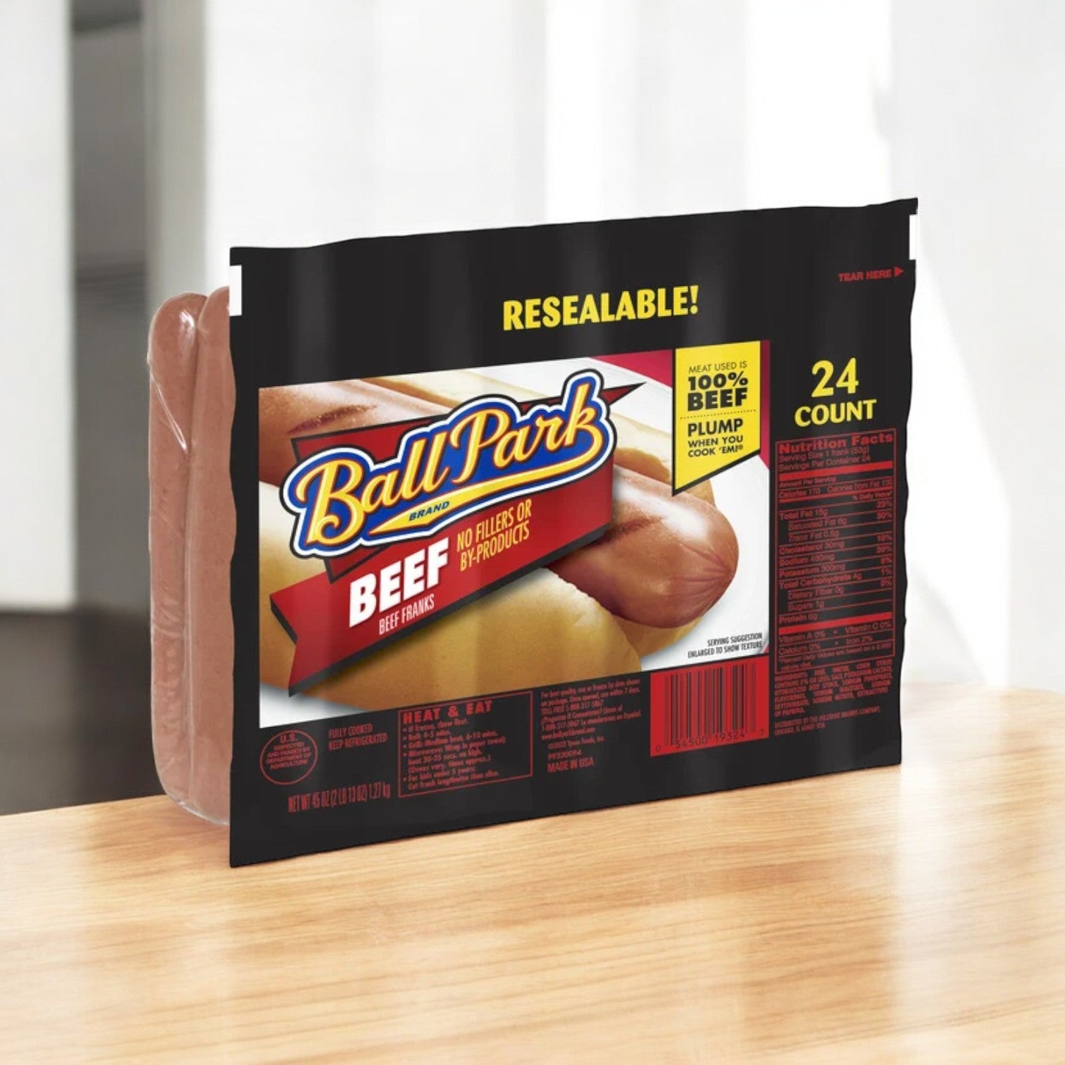 A pack of Ball Park Beef Franks, Original Length, 24 Count 1 Pack, ideal for grilling, sits on a wooden surface. Labeled as 100% beef with a resealable design, it's ready for your barbecue.