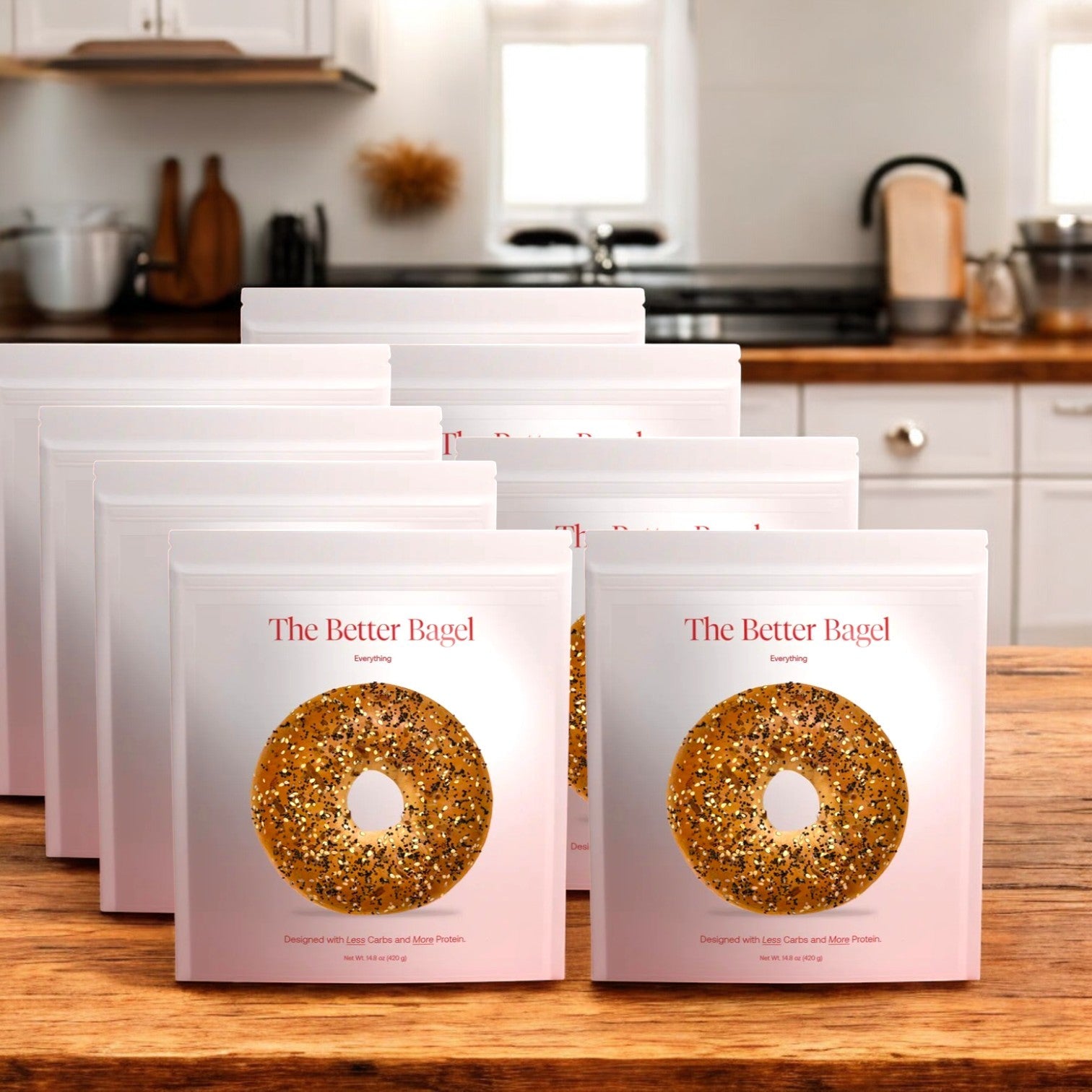 Eight bags containing 32 total "The Everything Better Bagel" by BetterBrand, featuring the iconic Everything Bagel image, are elegantly displayed on a wooden counter. This savory blend adds a gourmet touch to any kitchen, making breakfast delightful. In stock and ready to ship!.