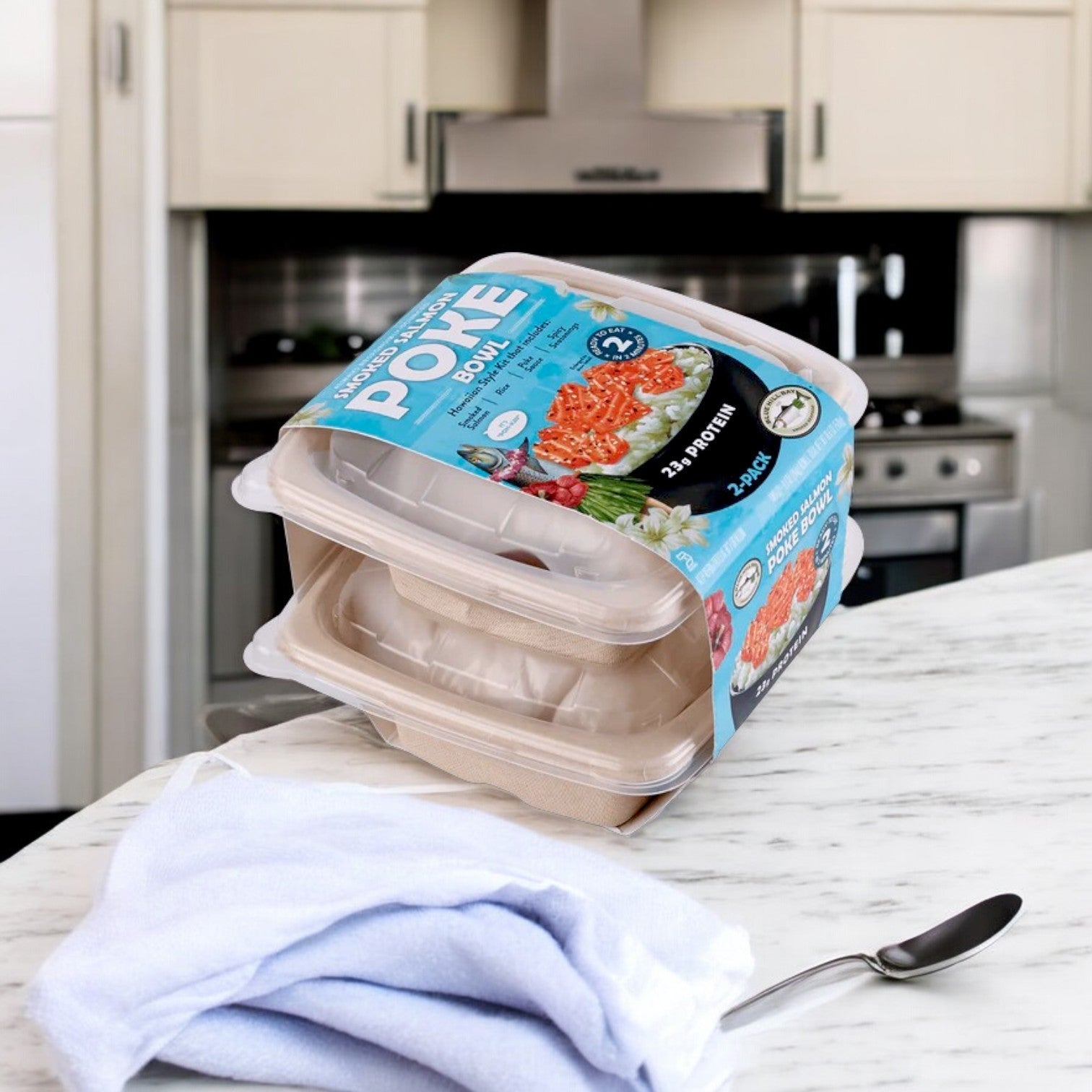 Two containers of Blue Hill Bay Smoked Salmon Poke Bowl, 9.3 oz each, sit stacked on a marble countertop with a cloth and spoon nearby. The sleek appliances in the background make it convenient for any kitchen setting.