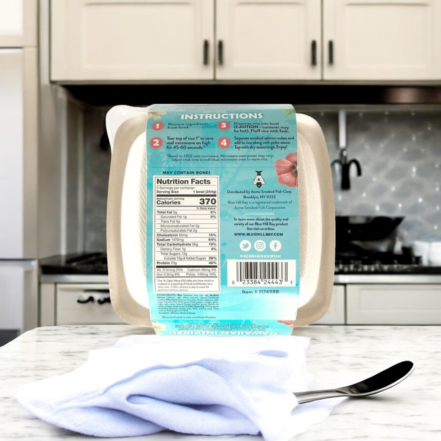 The Blue Hill Bay Smoked Salmon Poke Bowl package, 9.3 oz, 2 Count is prominently placed on the counter with its nutritional info and instructions visible. A spoon lies nearby on a white cloth, ready for a gourmet seafood experience delivered to your door.