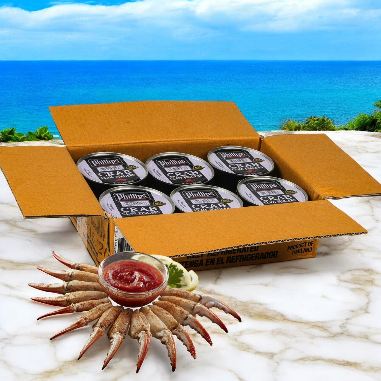 A case of Phillip Foods Crab Claw Finger Pasteurized Asia, 12 oz. - 6 cans, elegantly graces a marble surface alongside crab claws and sauce, set against the stunning backdrop of ocean and sky.